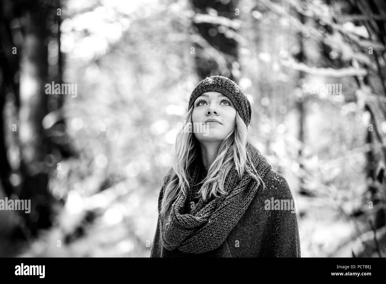 Mujer joven con el pelo rubio en el bosque, mirando hacia arriba Foto de stock