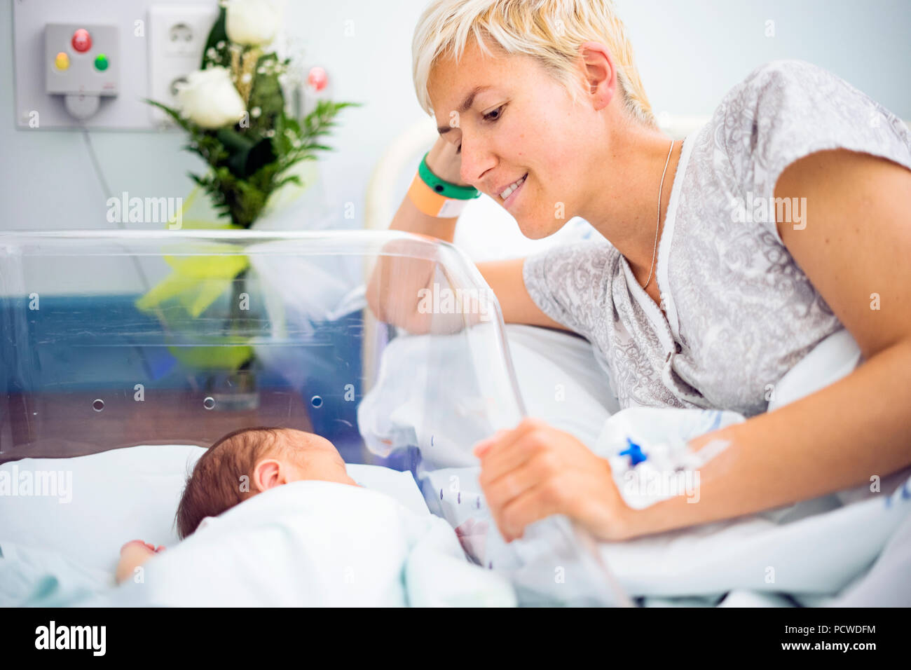 Madre mirando con amor a su bebé recién nacido niño aún en el hospital Foto de stock