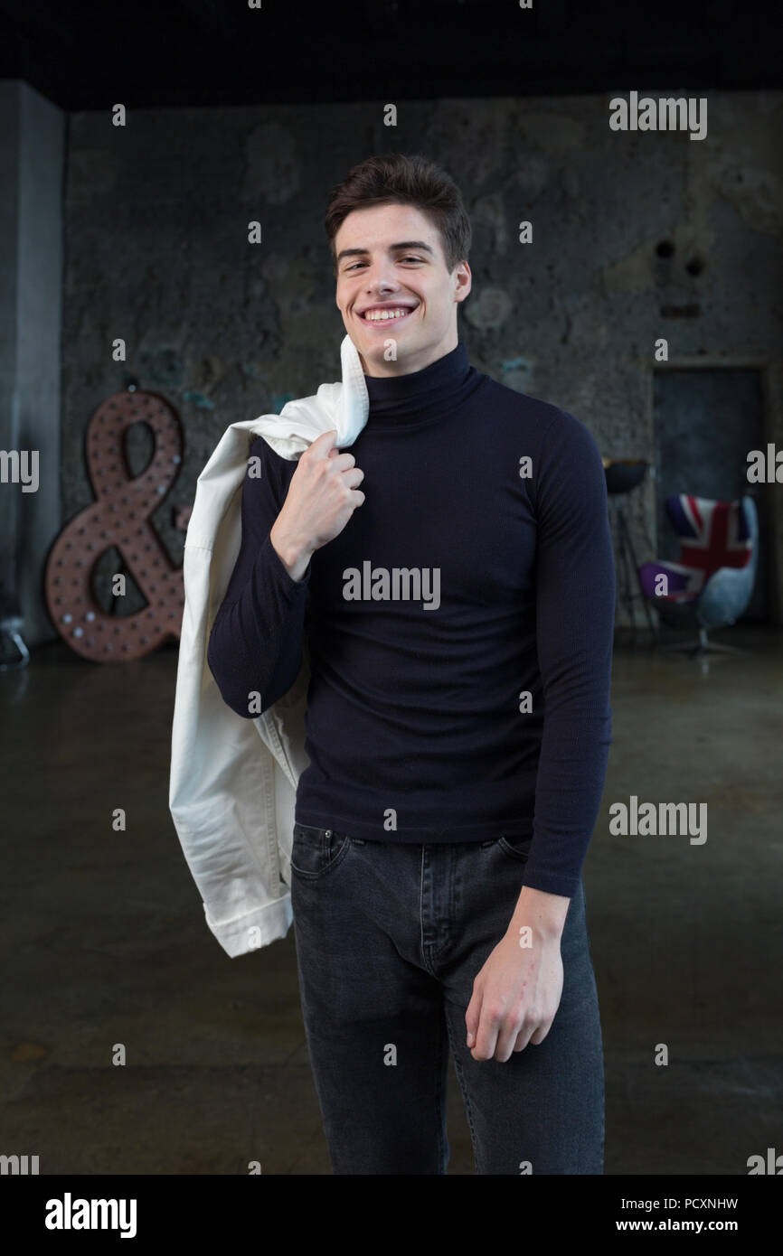 Apuesto positivo chaqueta hombre vestido de blanco y negro, pantalones  vaqueros en un interior moderno Fotografía de stock - Alamy