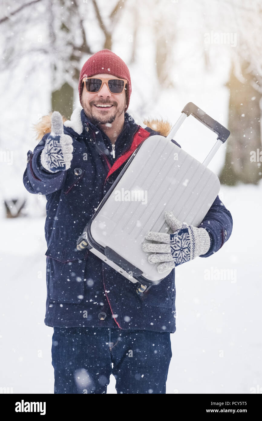 Hombre sonriente feliz en gafas de sol posando en la nieve al aire libre