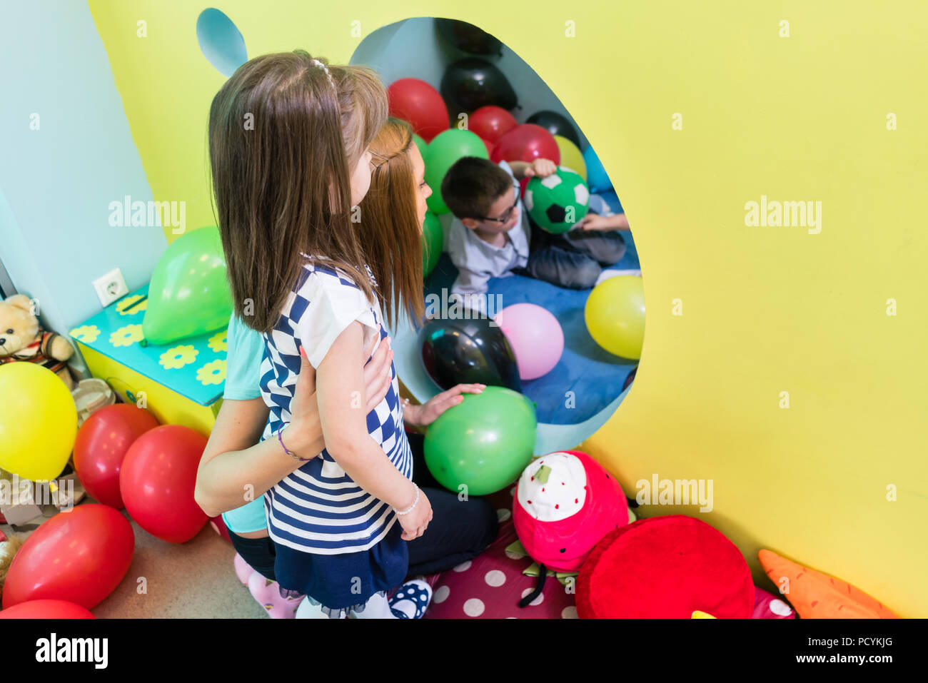 Cuidado maestro orientar una tímida niña de pre-escolar durante el tiempo de juego Foto de stock