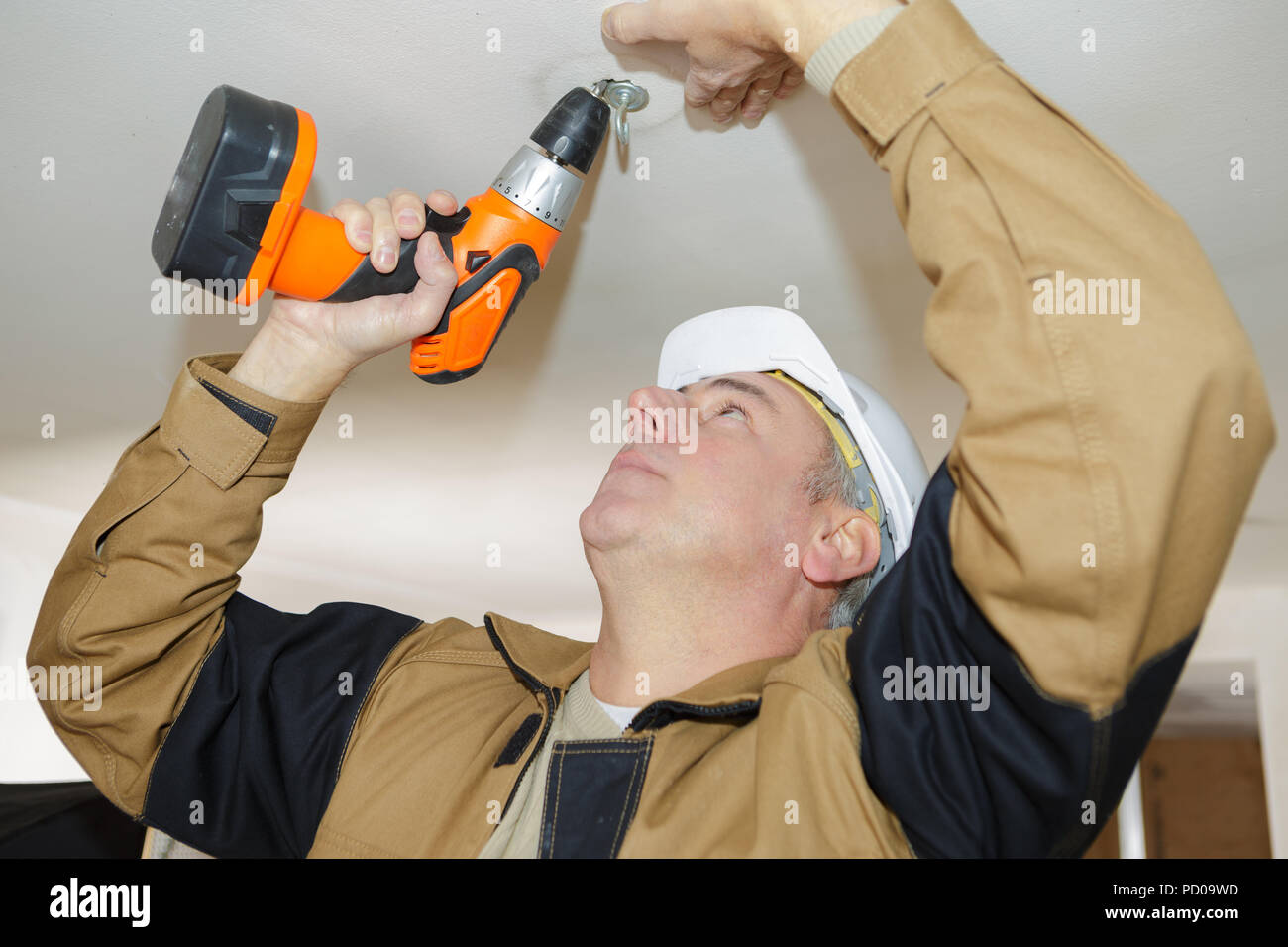 El hombre es taladrar agujeros en el techo de hormigón con máquina de  perforación Fotografía de stock - Alamy
