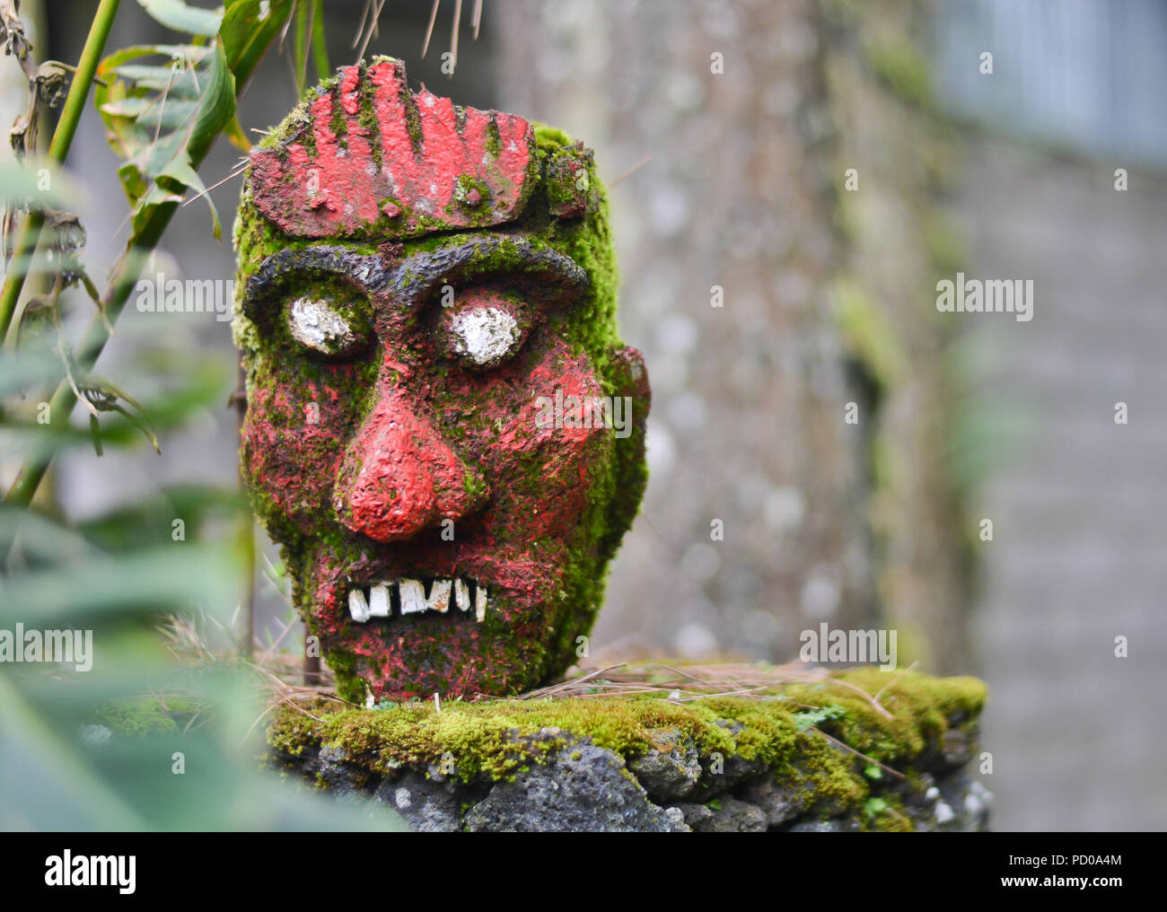 Máscara Roja del ídolo de la antigua religión de Bali con blanco ojos protruyentes en un stand en la selva. Foto de stock