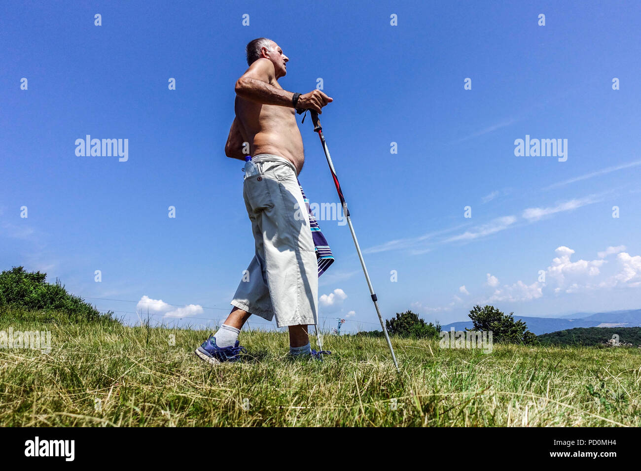 Hombre mayor con bastones de marcha nórdica en el prado de la montaña, Velka Javorina, anciano de Eslovaquia Foto de stock