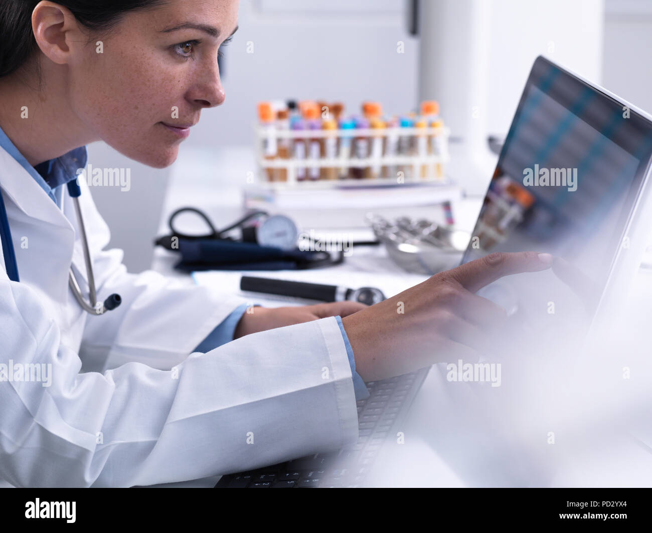 Doctor accediendo a pacientes detalles utilizando un equipo con pantalla táctil en la clínica Foto de stock