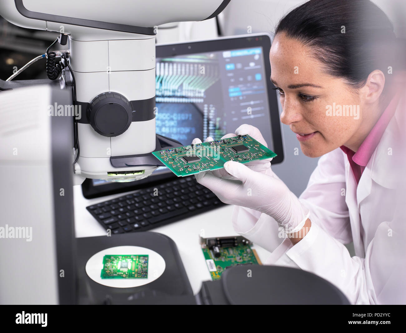 Ingeniero servo 3D utilizando microscopio para ver la precisión dimensional de manufacturas de montaje en PCB Foto de stock