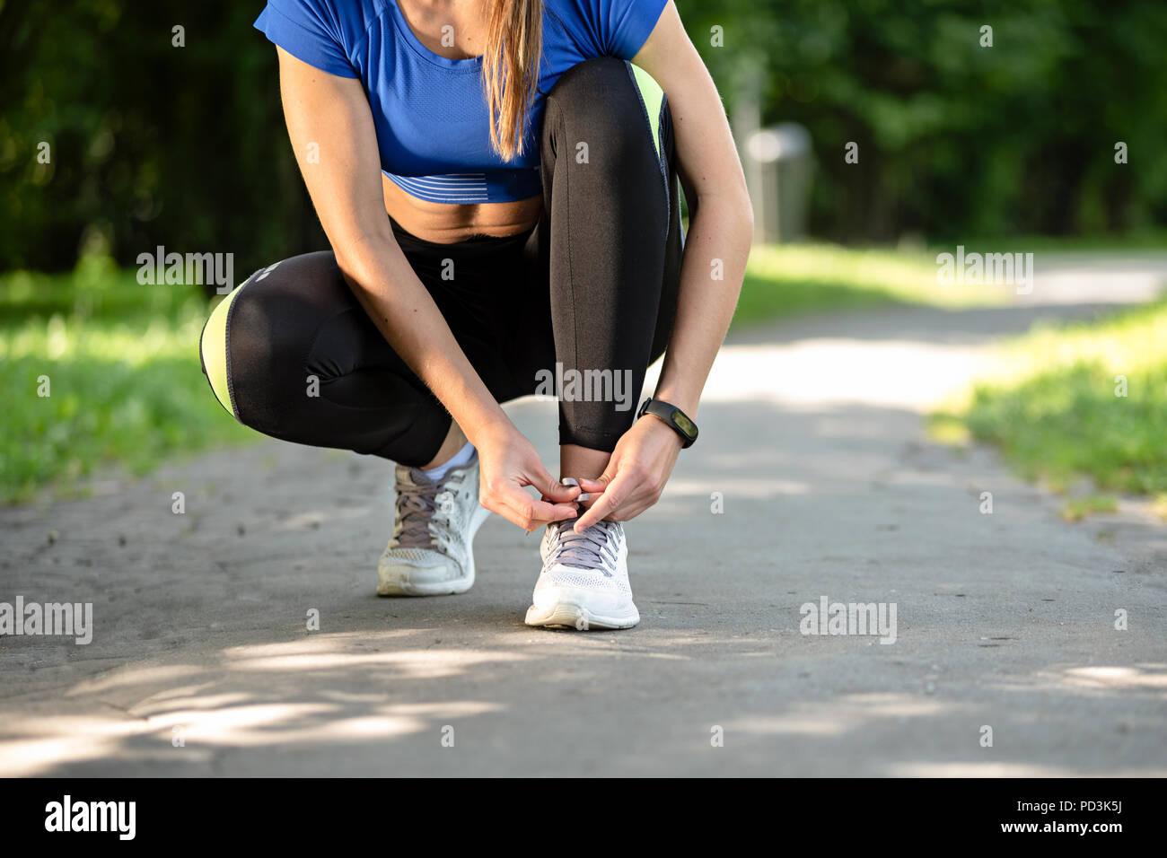 Fitness mujer Cordones de atado con zapatillas durante el ejercicio al aire  libre en el parque en una mañana soleada Fotografía de stock - Alamy