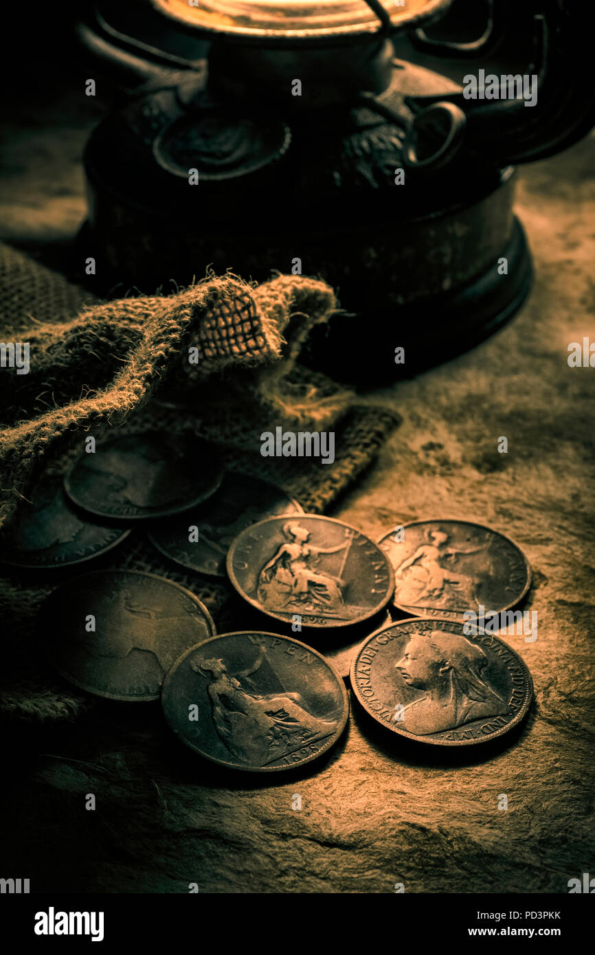 Antiguas monedas penny británica iluminada por una lámpara de aceite. Foto de stock