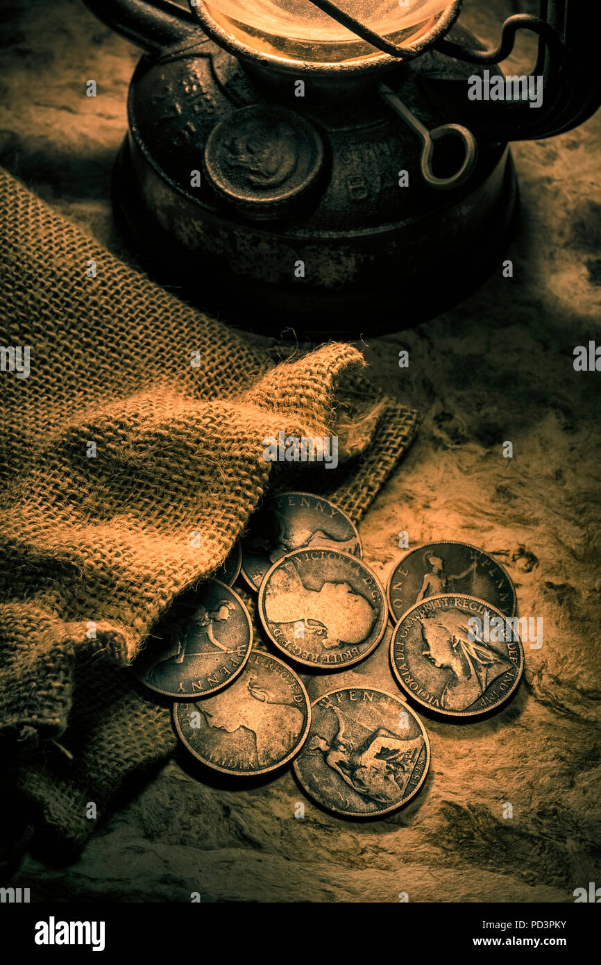 Antiguas monedas penny británica iluminada por una lámpara de aceite. Foto de stock