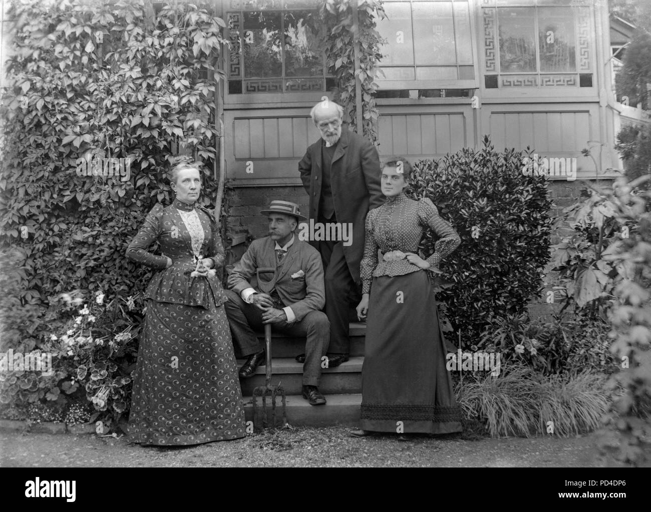 A finales de la época victoriana fotografía de un grupo de personas fuera de una casa en Inglaterra. Hay un Vicario, un jardinero y dos mujeres. Presumiblemente, las personas que trabajan en la casa. Foto de stock