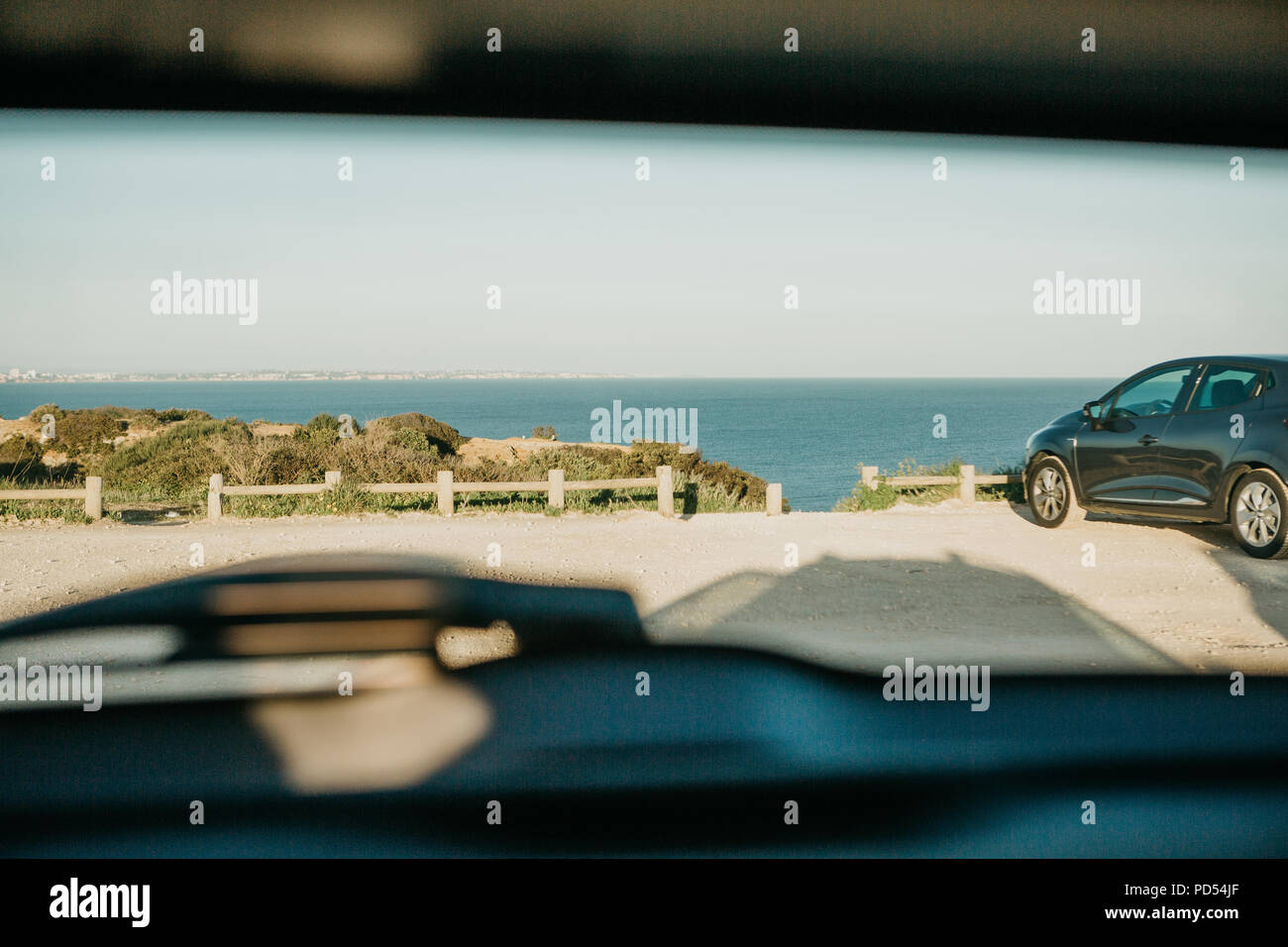 Ver a través de la ventana trasera del coche en el estacionamiento de una fila con el mar o el océano en el verano. Imagen conceptual del verano viajes en coche. Foto de stock