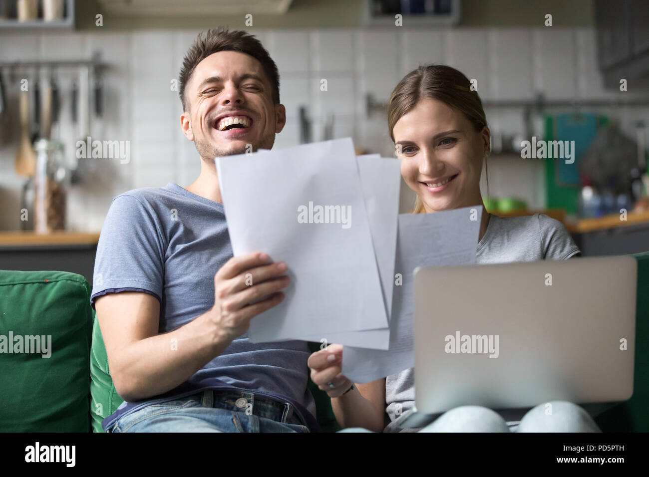 Feliz pareja riendo divirtiéndose con documentos y ordenador portátil Foto de stock