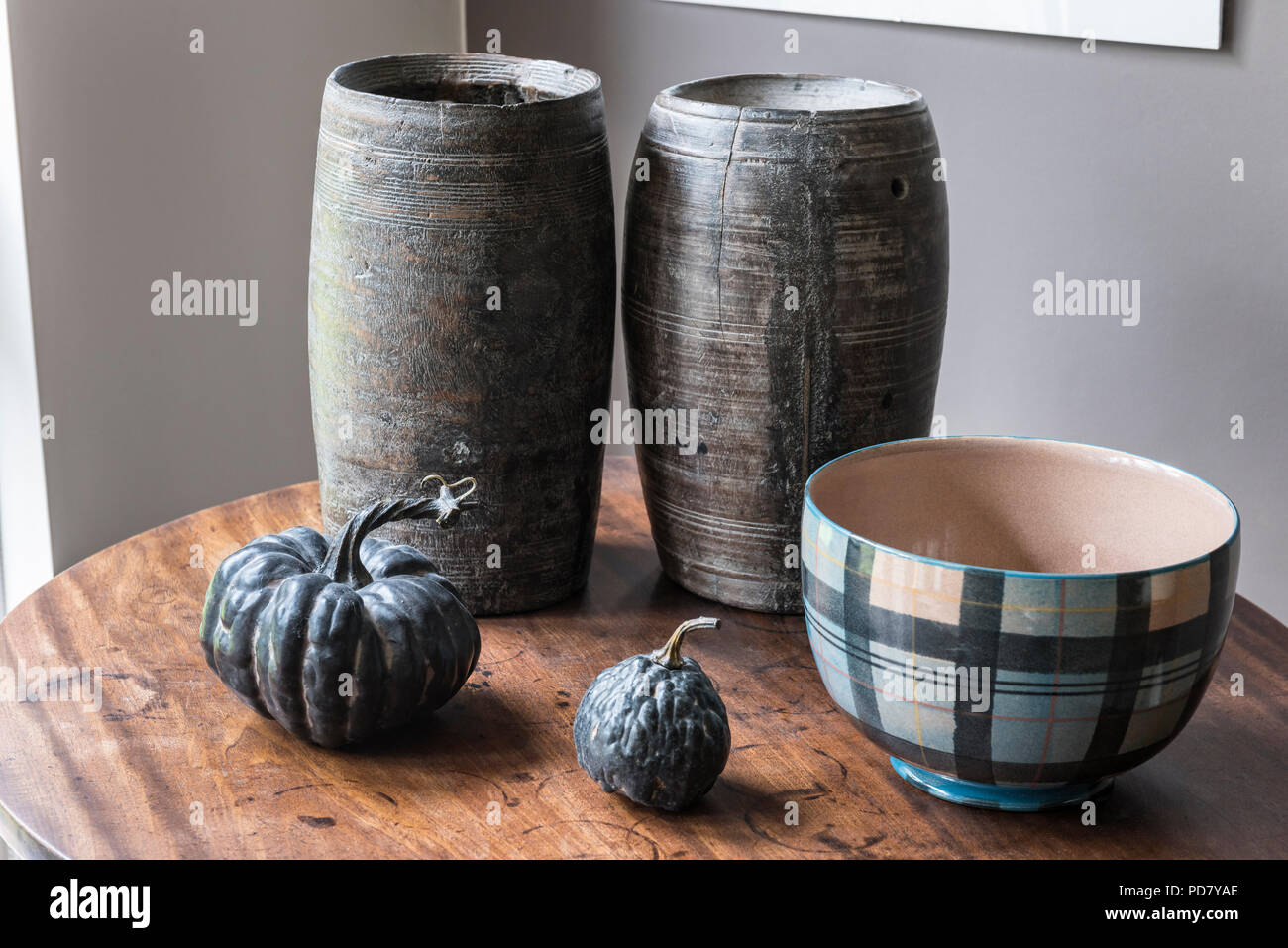 Dos botes de madera de Sudáfrica son mostrados en una pequeña mesa en el salón con calabazas secadas y un cuenco de Anta. Foto de stock