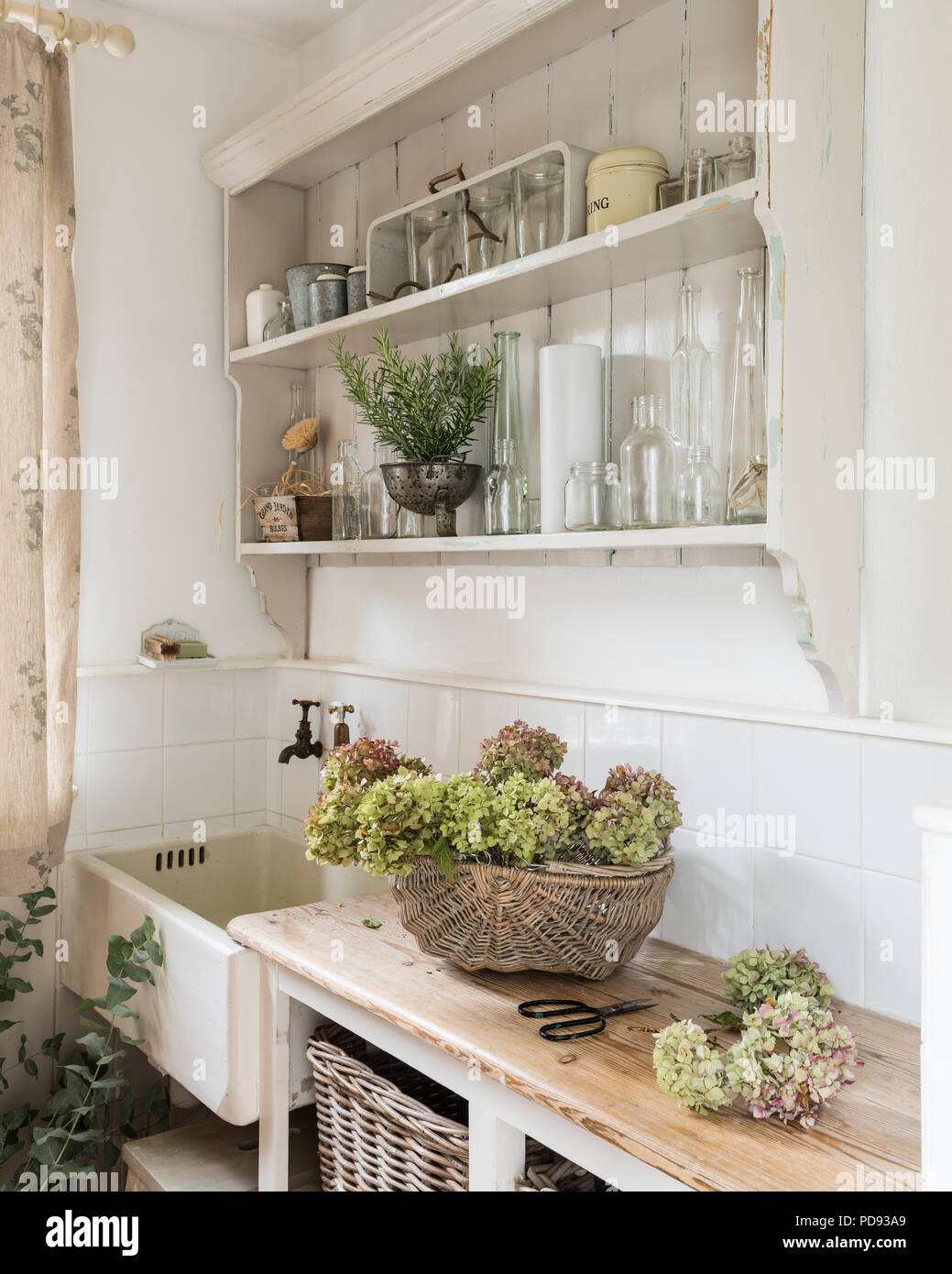 Hydrangea secos jefes en rincón de cocina en estilo rústico con lavabo de cerámica y estanterías de madera abiertas Foto de stock