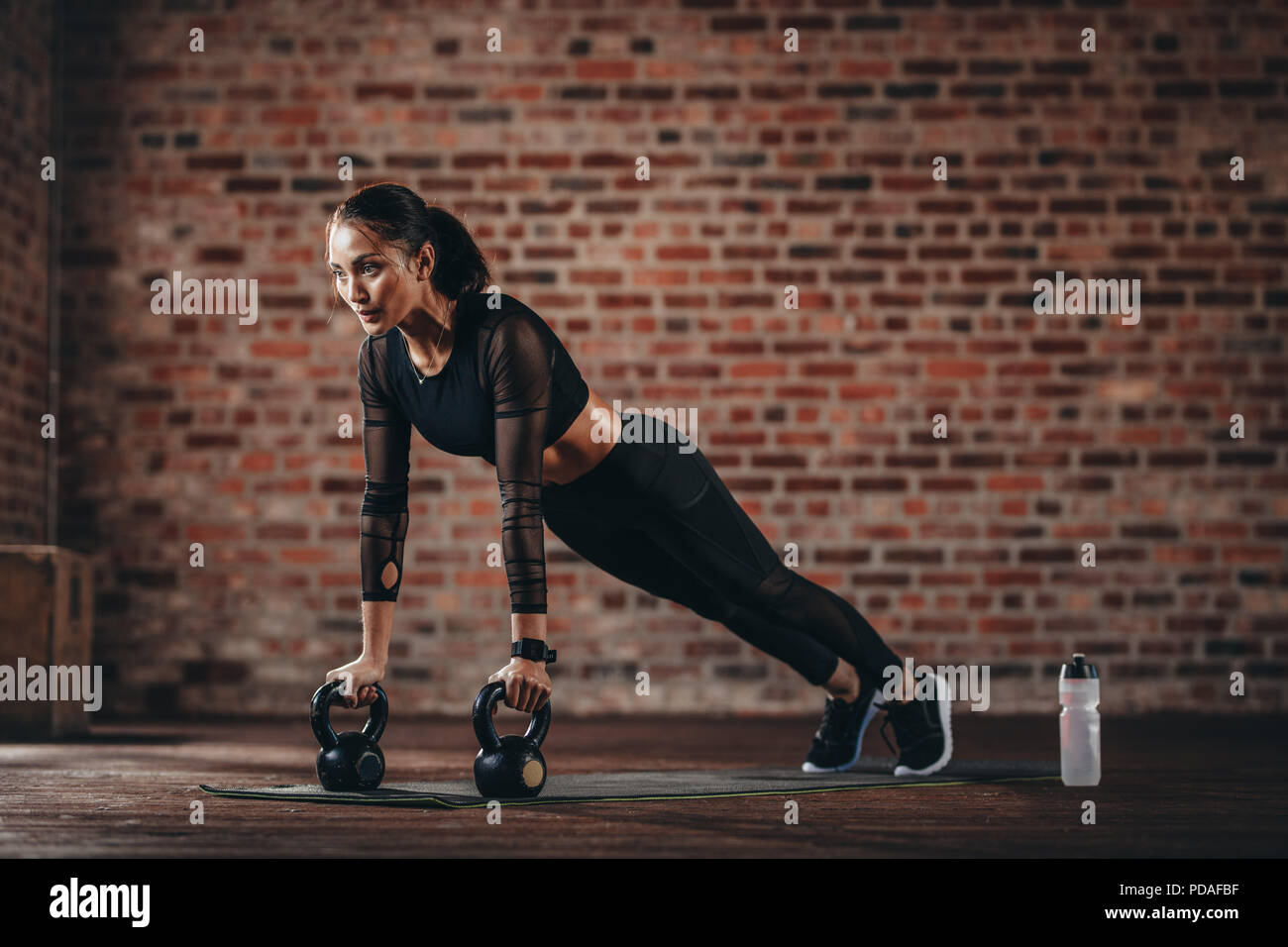 fitness mujer haciendo flexiones con campana de tetera en el gimnasio. Atleta femenina haciendo entrenamiento cruzado en el gimnasio. Foto de stock