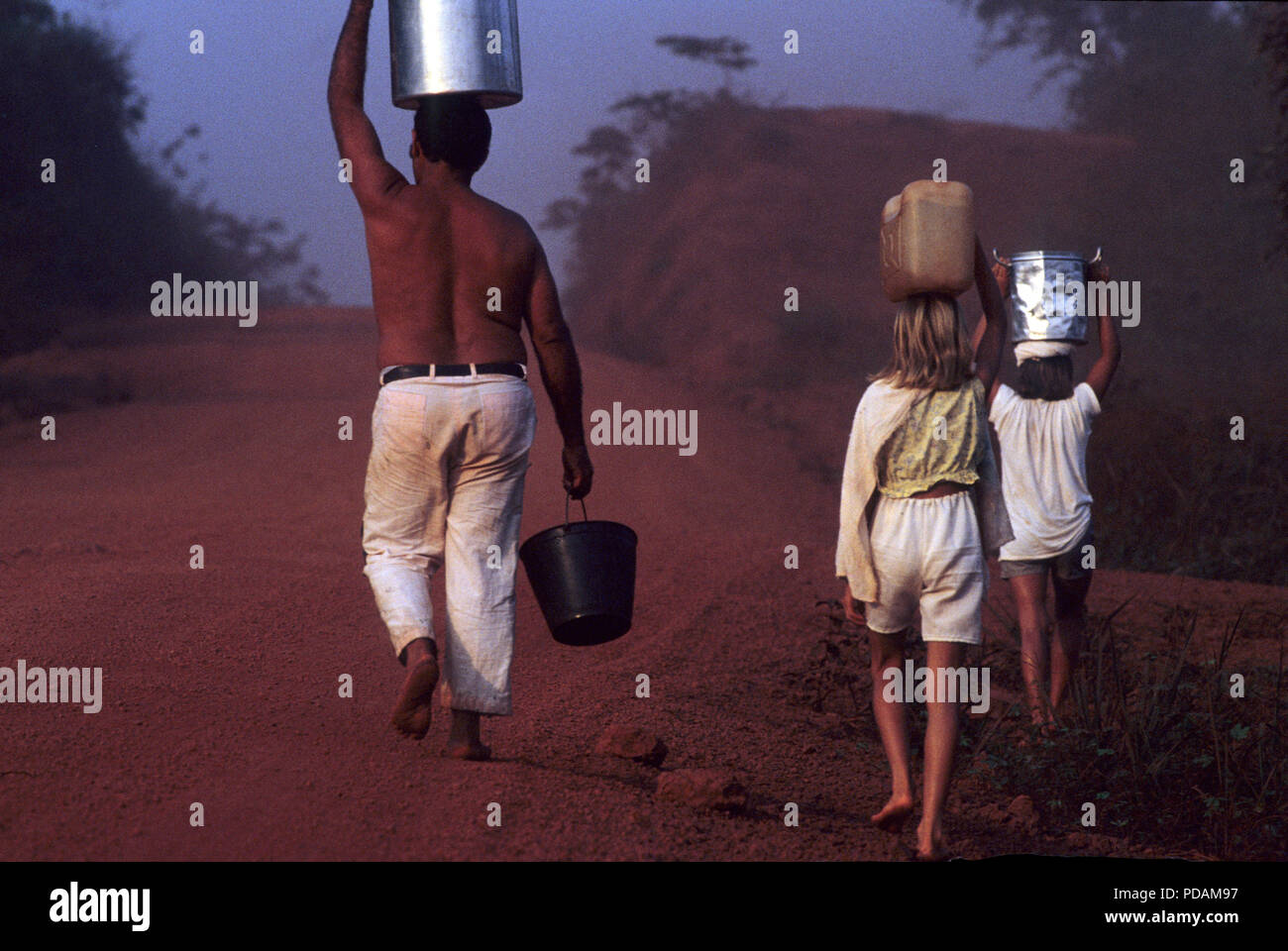 Familia de colonos, el padre y los hijos llevar cubos de agua en la carretera Transamazonica, Estado de Pará, Amazonas, en el norte de Brasil. Foto de stock