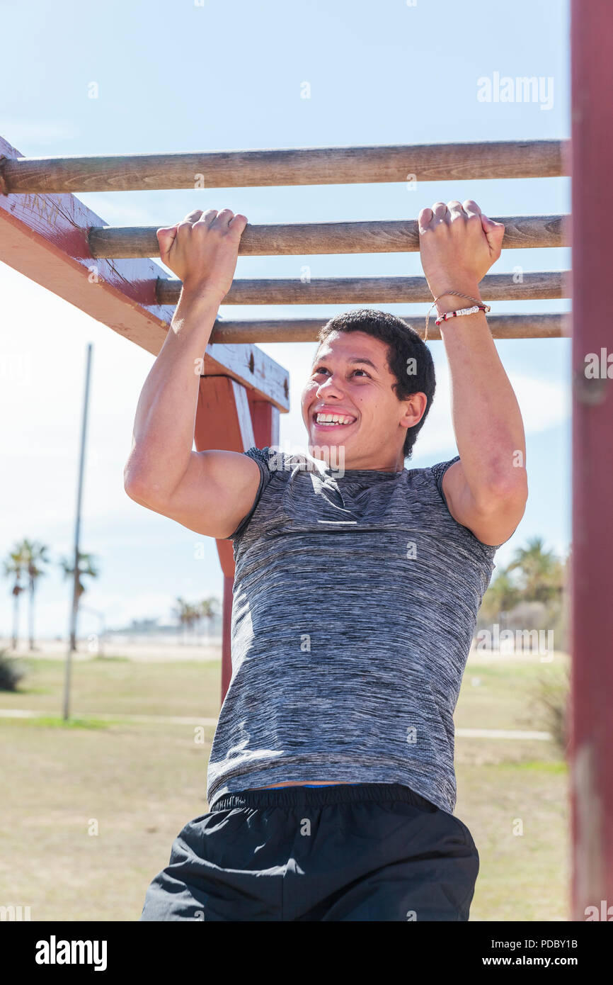 Determinado hombre haciendo pull-ups en monkey bares Foto de stock