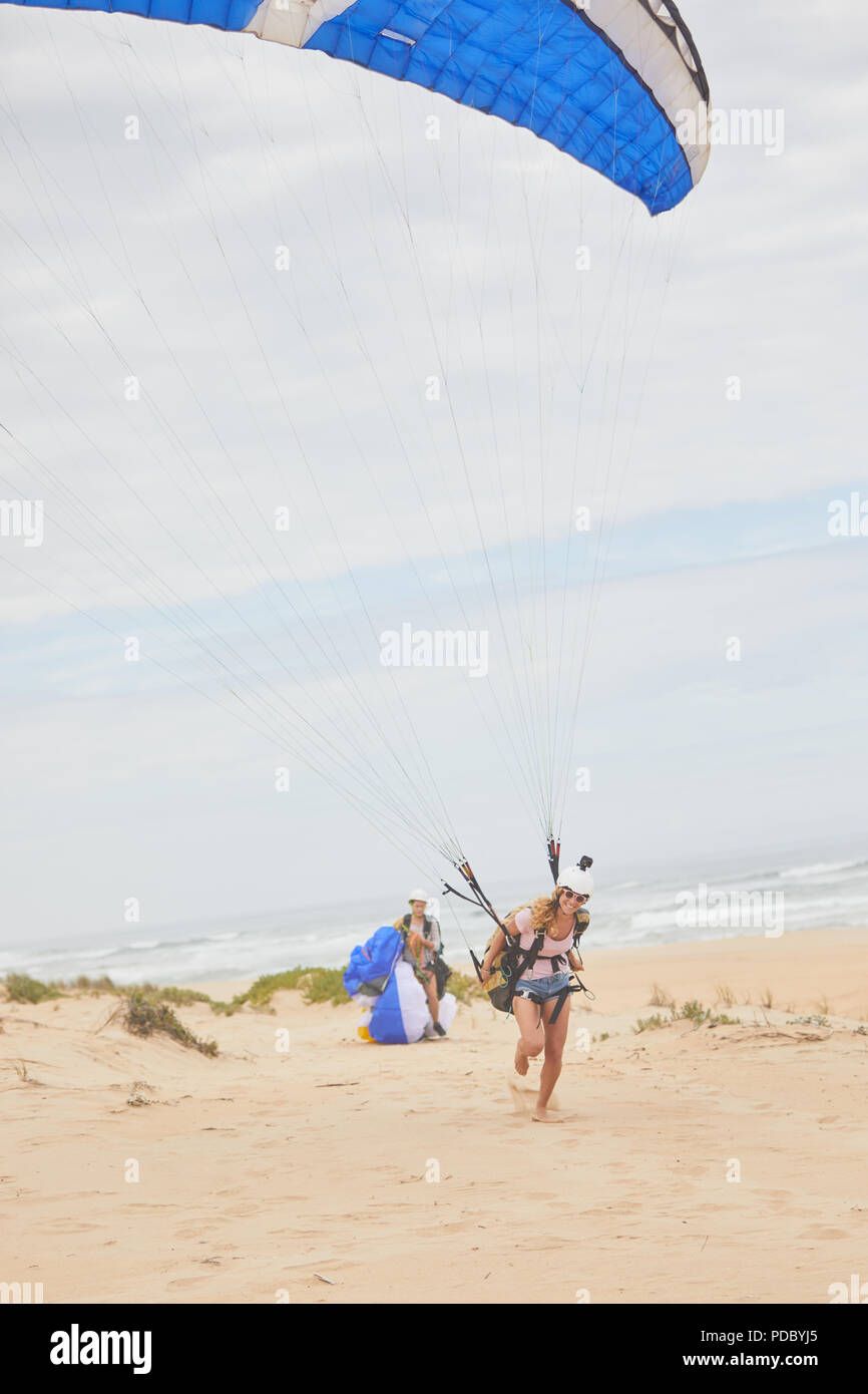 Hembra parapente con paracaídas en la playa. Foto de stock