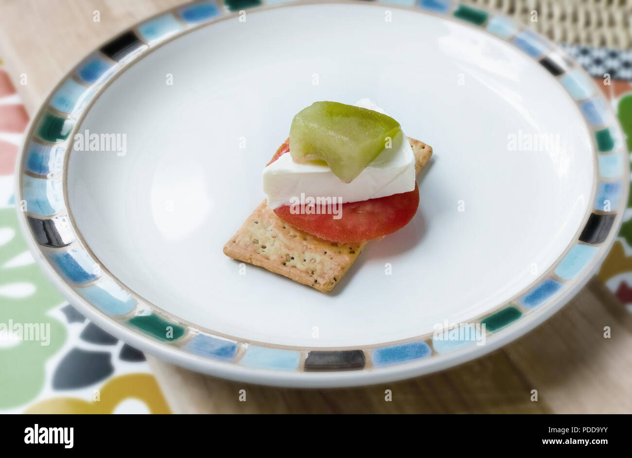 En la placa, en una galleta salada, tenemos una rodaja de tomate, queso, un trozo de melón Foto de stock