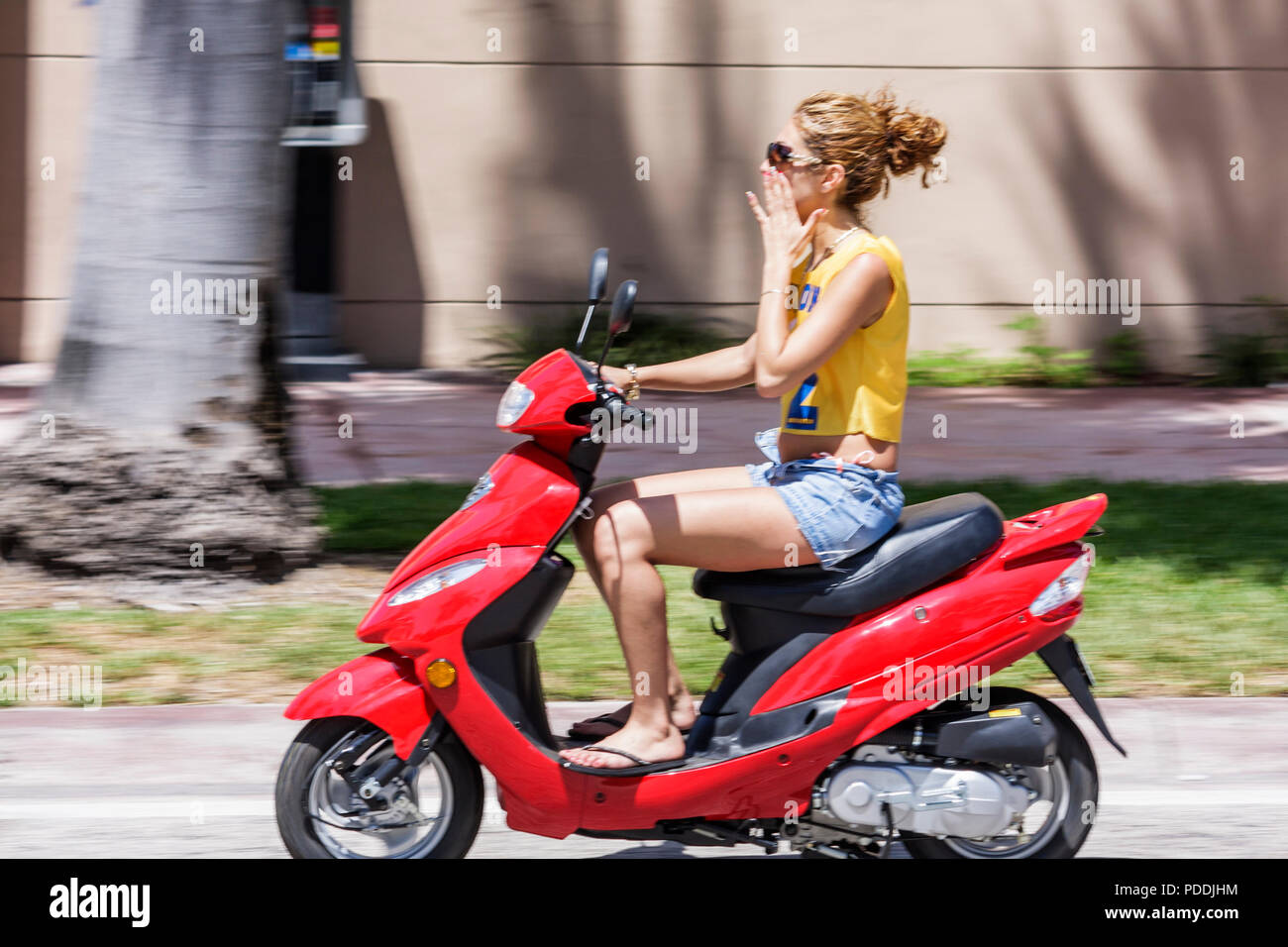 Miami Beach Florida,Fifth 5th Street,adultos mujer mujer mujer mujer mujer dama,rojo,motonoters,paseo,ciclomotor,motocicletas,alternativa tra Foto de stock