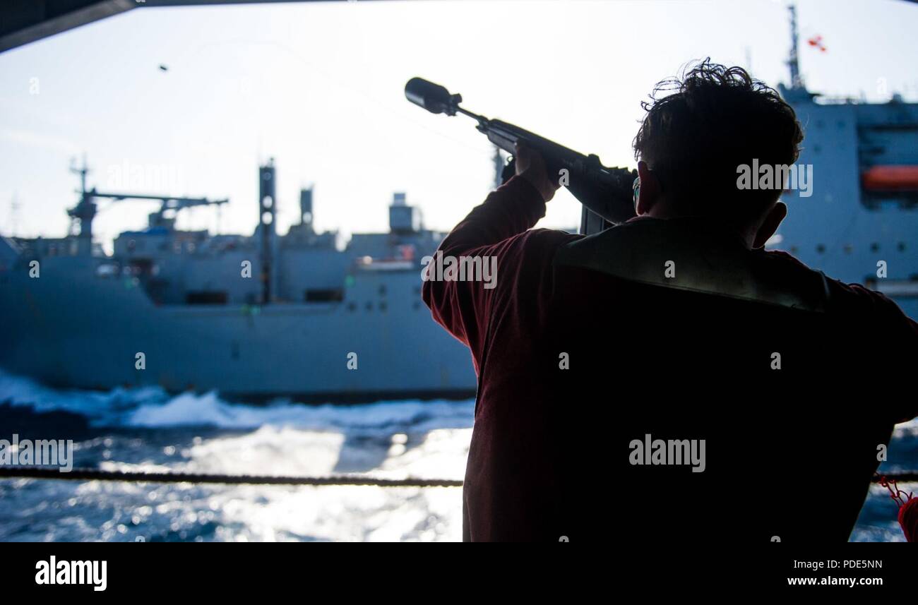 Las aguas al sur de Japón (15 de mayo de 2018) Aviador reclutar Micah Spinella, de Bakersfield, California, desencadena un mensajero a la línea de comando de Transporte Marítimo Militar (MSC) carga seca/municiones buque USNS César Chávez (T-AKE 14), desde el hangar bay a bordo de la Marina desplegadas, el portaviones USS Ronald Reagan (CVN 76), como parte de una reposición en alta mar durante las pruebas de mar. Los civiles no combatientes, con tripulación de barco, operado por la MSC, proporciona el combustible, alimentos, municiones, piezas de repuesto, el correo y otros suministros a los buques de la Marina en todo el mundo. Ronald Reagan, el buque insignia de Carrier Strike Group 5, proporciona un combate- Foto de stock