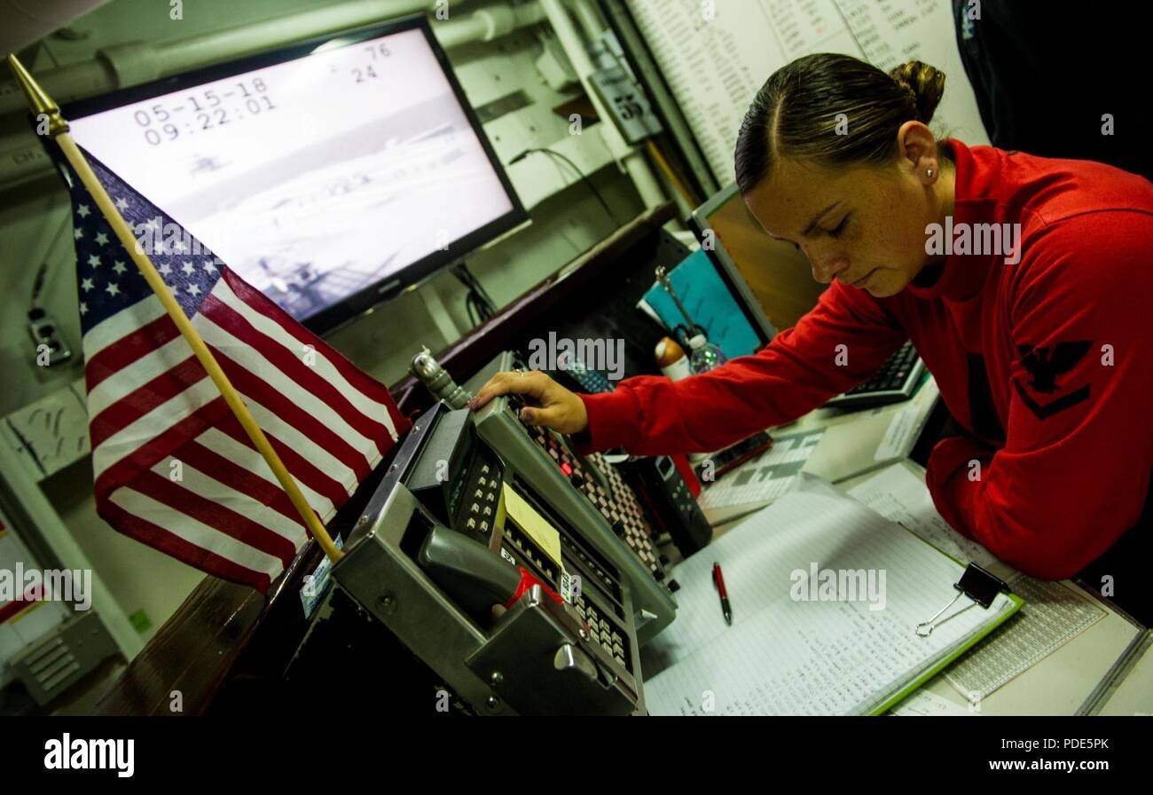 Las aguas al sur de Japón (15 de mayo de 2018) la aviación 3ª clase Ordnanceman Ashley Roden, de Chandler, Arizona, mans el pupitre de control de municiones a bordo de la Marina desplegadas, el portaviones USS Ronald Reagan (CVN 76), como parte de una reposición en alta mar con el comando de Transporte Marítimo Militar (MSC) carga seca/municiones buque USNS César Chávez (T-AKE 14), durante las pruebas de mar. Los civiles no combatientes, con tripulación de barco, operado por la MSC, proporciona el combustible, alimentos, municiones, piezas de repuesto, el correo y otros suministros a los buques de la Marina en todo el mundo. Ronald Reagan, el buque insignia de Carrier Strike Group 5, proporciona un combate-re Foto de stock