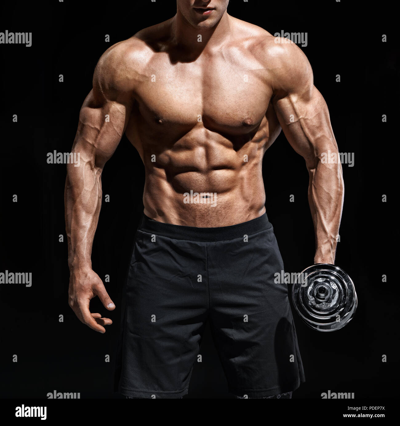 Cerca del hombre mostrando cuerpo musculoso y seis pack abs. Foto de hombre  descamisado con pesa sobre fondo negro. Fuerza y motivación Fotografía de  stock - Alamy