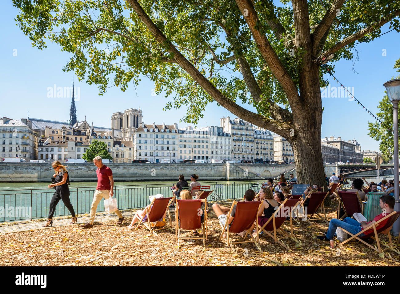 La gente descansando en hamacas a la orilla del Sena en París Plage Verano  de eventos en París, Francia, con la catedral Notre-Dame de París en el  fondo Fotografía de stock -