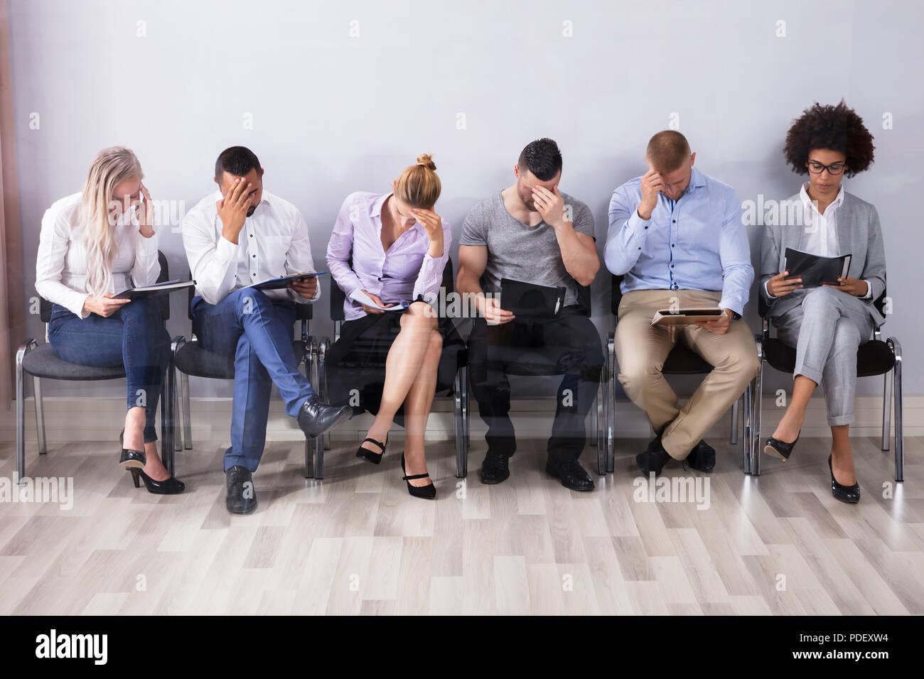 Aburrido personas sentadas en una fila de espera para una entrevista de  trabajo Fotografía de stock - Alamy