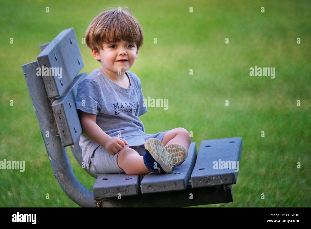 dañoso pequeño niño, preescolar niña 4 4 años sonriente mirando a cámara,  sentado en un mosaico banco en el ciudad parque 27052714 Foto de stock en  Vecteezy