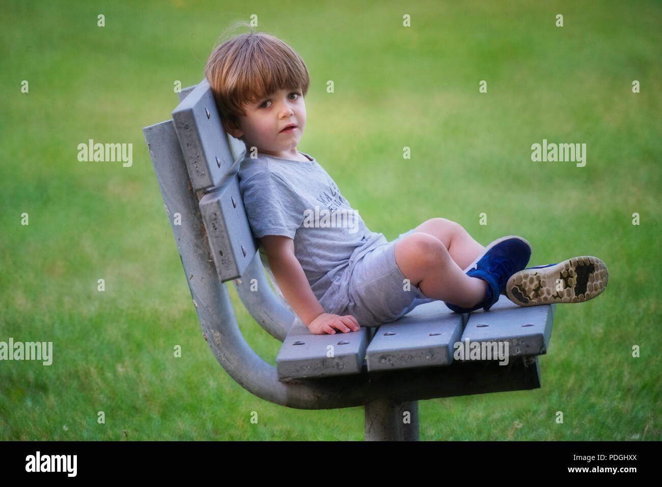 dañoso pequeño niño, preescolar niña 4 4 años sonriente mirando a cámara,  sentado en un mosaico banco en el ciudad parque 27052714 Foto de stock en  Vecteezy