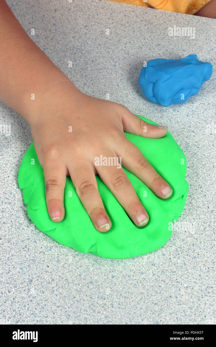 Los niños haciendo una impresión de mano en algunos plastilina azul. Foto de stock