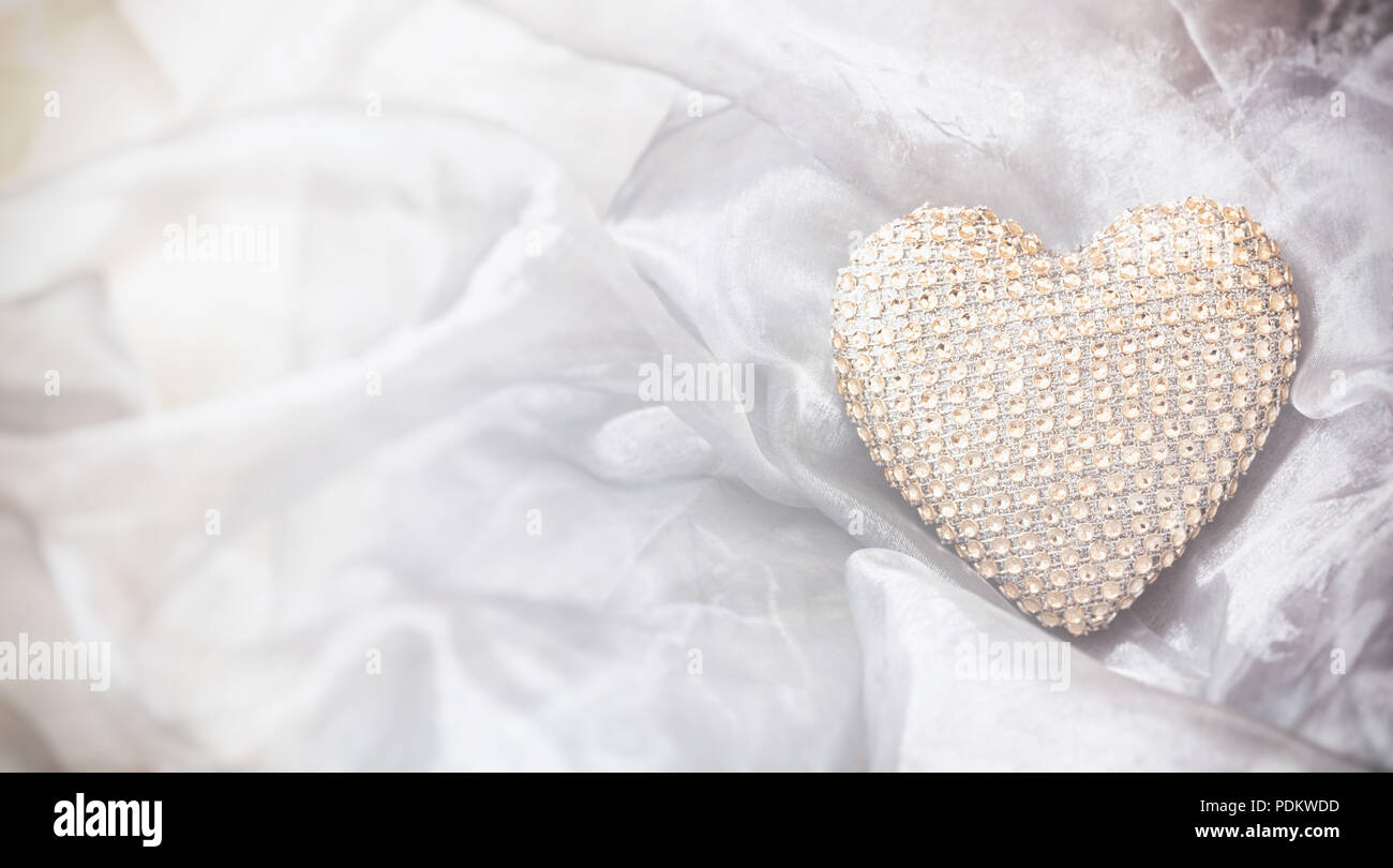 Amor y matrimonio concepto. Golden sequin corazón, vista superior, copia el espacio, sobre un fondo de tul de seda blanca. Foto de stock