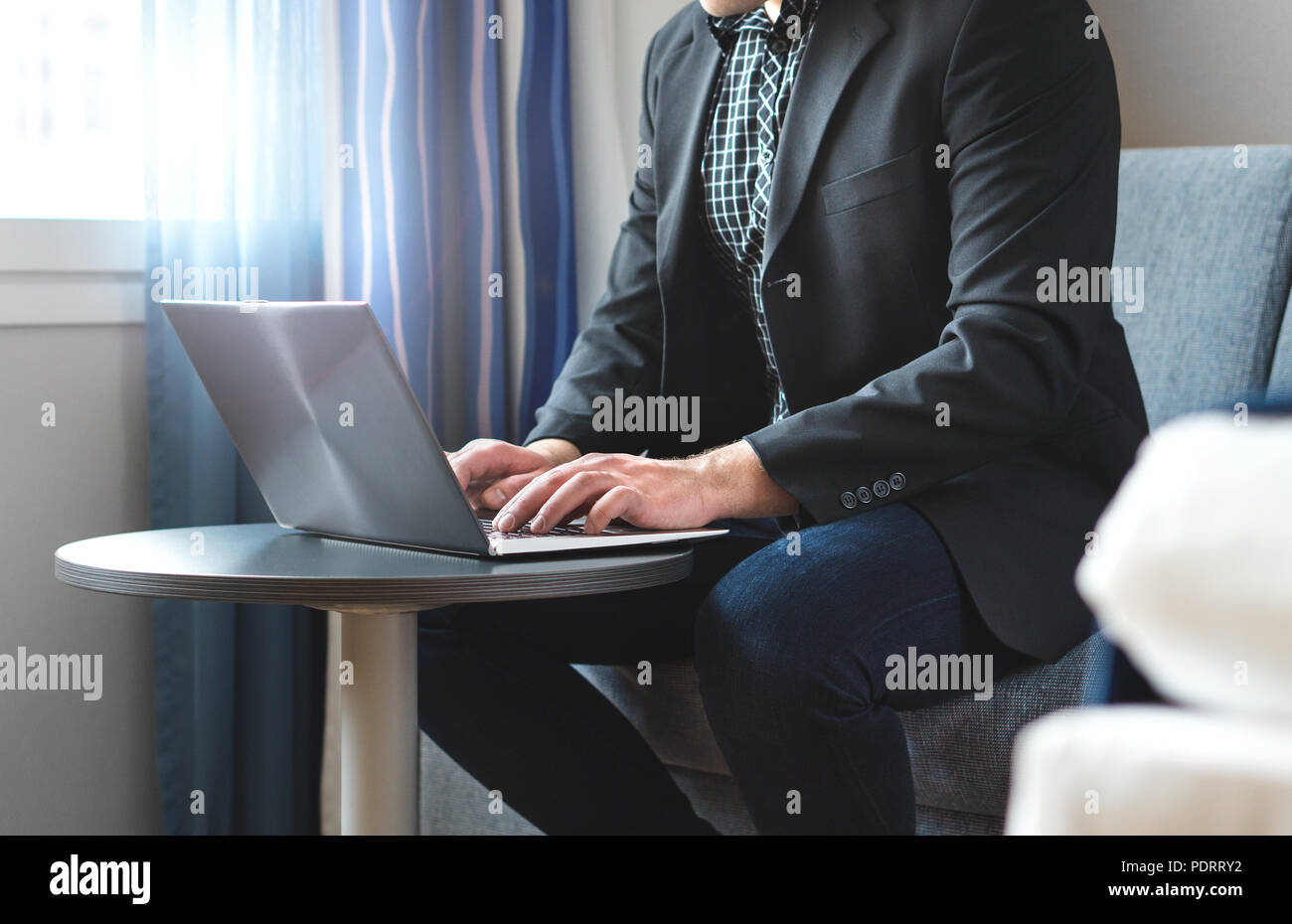Hombre de negocios que trabajan con ordenador portátil en la habitación del hotel. Empresario haciendo el trabajo con el ordenador remoto. Persona sentada y escribiendo. Foto de stock
