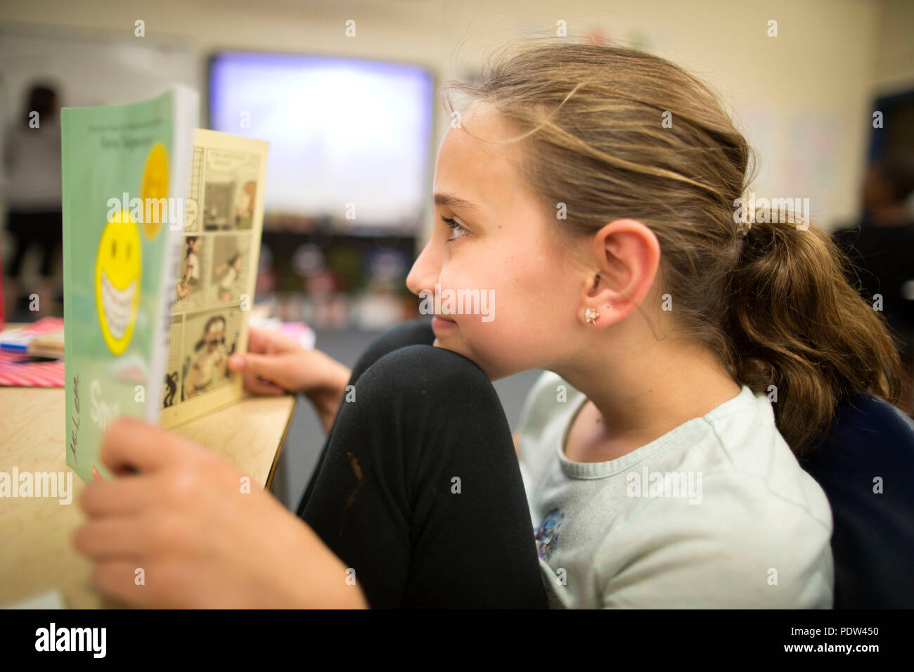 Una niña de cuarto grado lee una novela gráfica en un aula de Wisconsin. Foto de stock