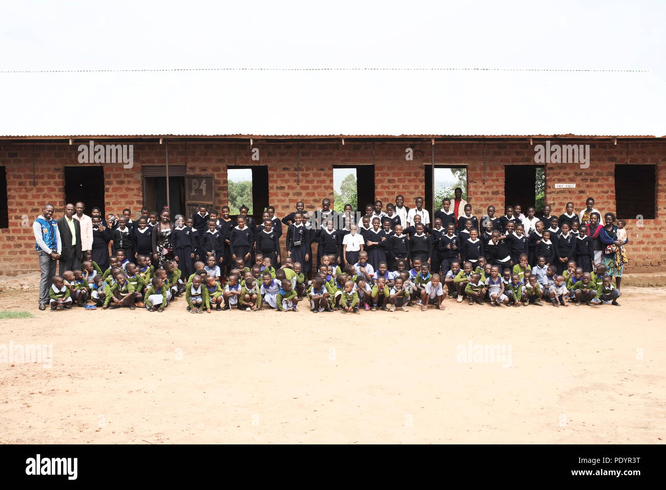 foto de grupo grande de una pequeña escuela ugandesa posando con maestros para la foto de la escuela Foto de stock