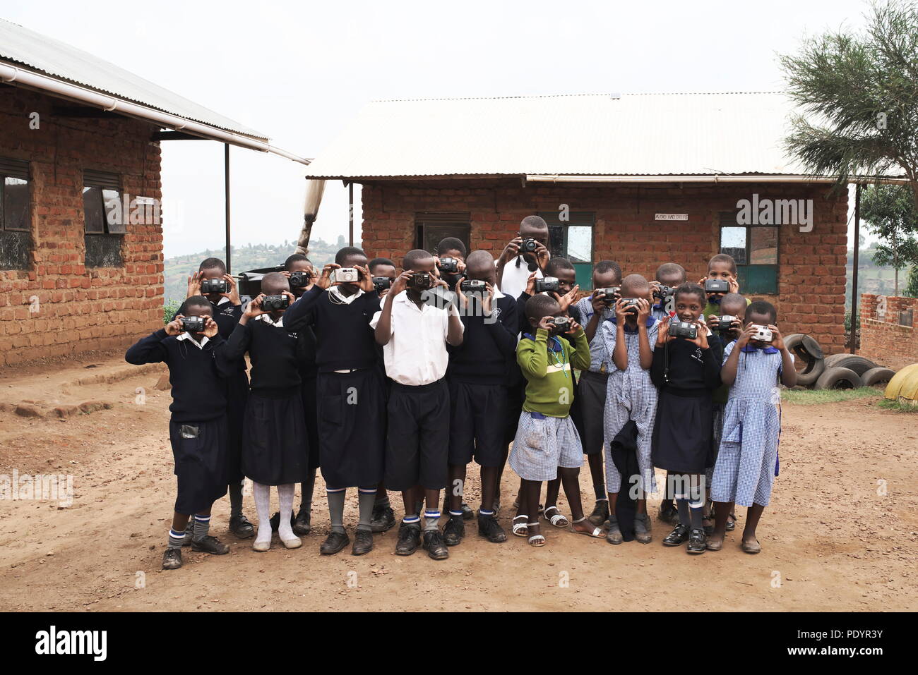 Pequeño grupo de niños ugandeses posando para fotos de grupo con cámaras en el campo ugandés Foto de stock