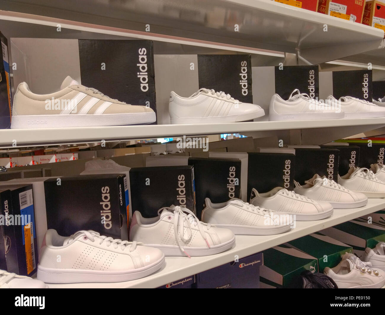 Zapatillas Adidas blancas muestran en las estanterías en la tienda de  zapatos Fotografía de stock - Alamy