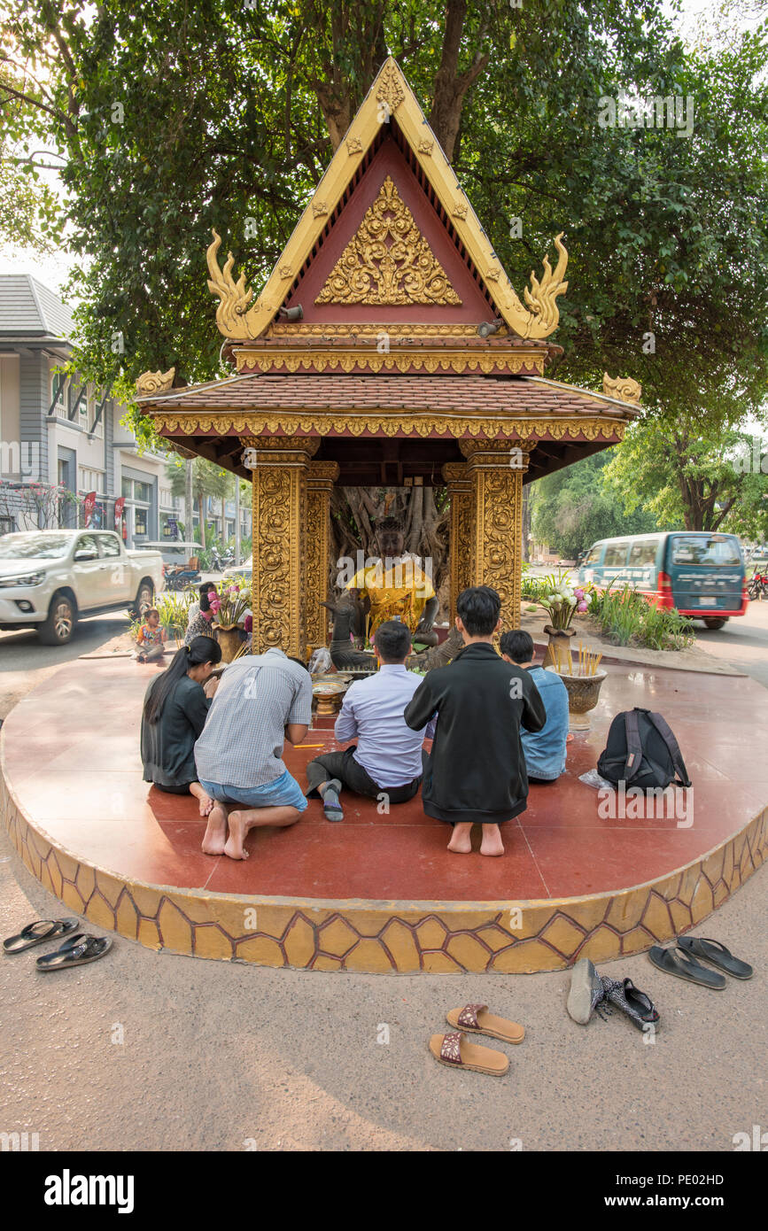 Adoradores de Camboya rezando delante del rey Master estatua situada debajo de un árbol y en medio de la carretera, Siem Reap, Camboya Foto de stock