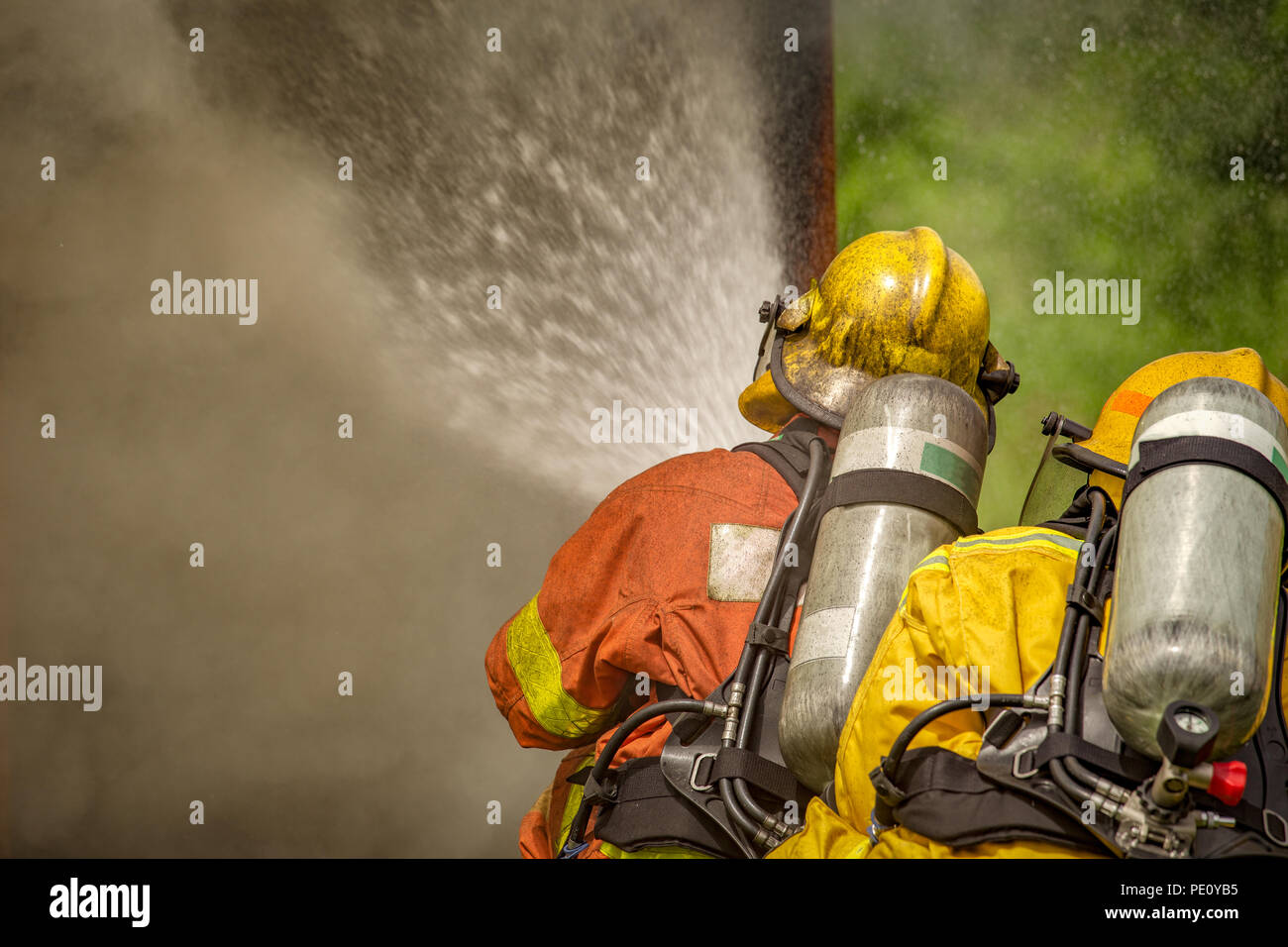 La acción de cierre de dos bomberos de pulverización de agua de alta presión por la boquilla al fuego y humo, con copia espacio en tono cinematográfico Foto de stock