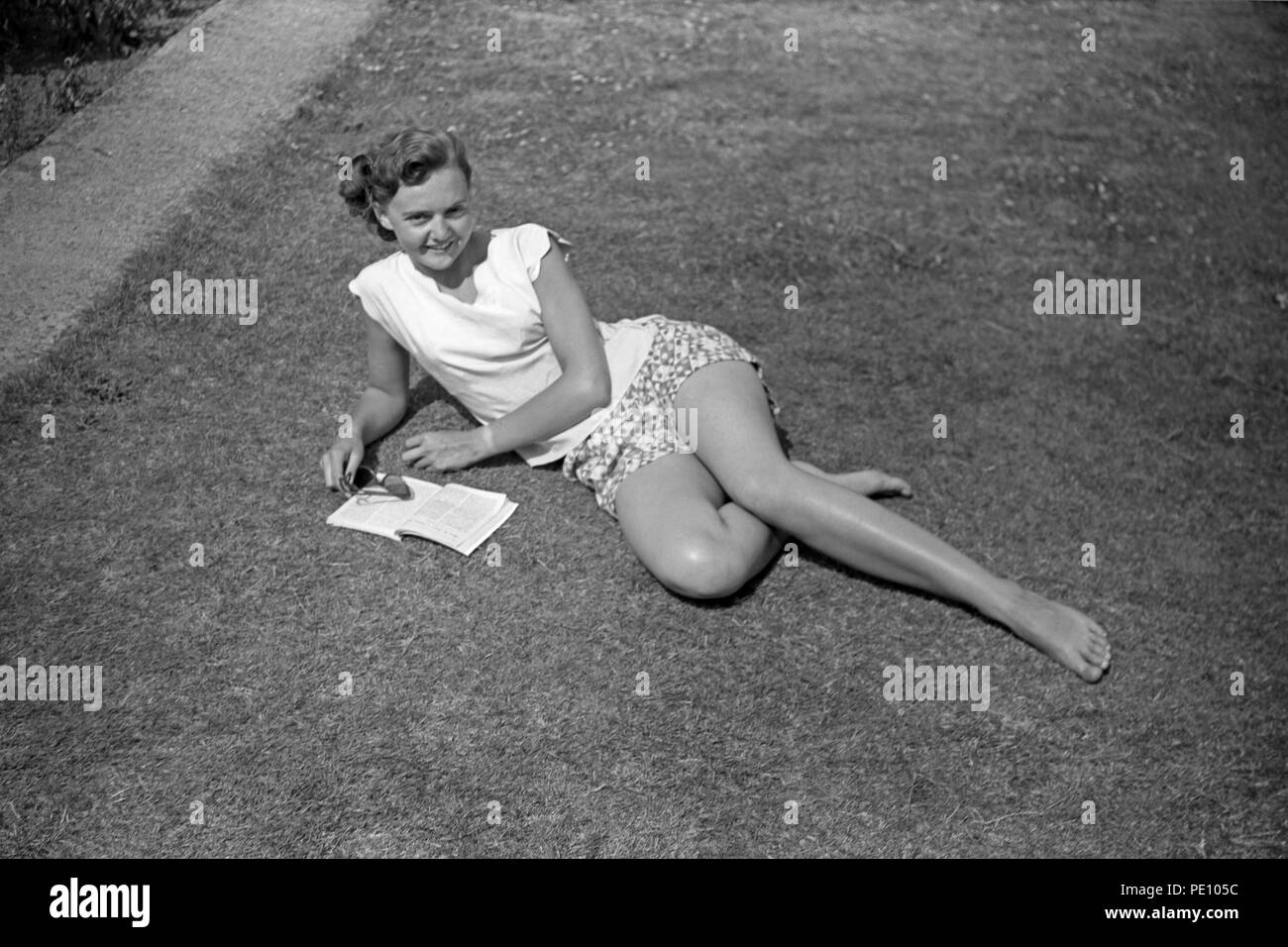 Atractiva señorita descansando en el césped leyendo Foto de stock