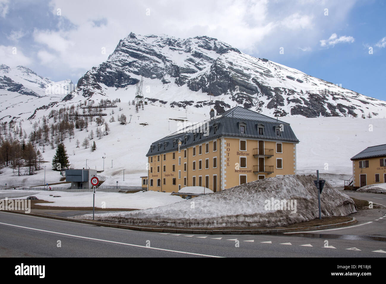 Bellevue Hotel y restaurante al lado de la carretera E62 Simplonstrasse en el lado norte del Simplon Pass en Suiza con los bancos de nieve a los lados de la carretera y s Foto de stock