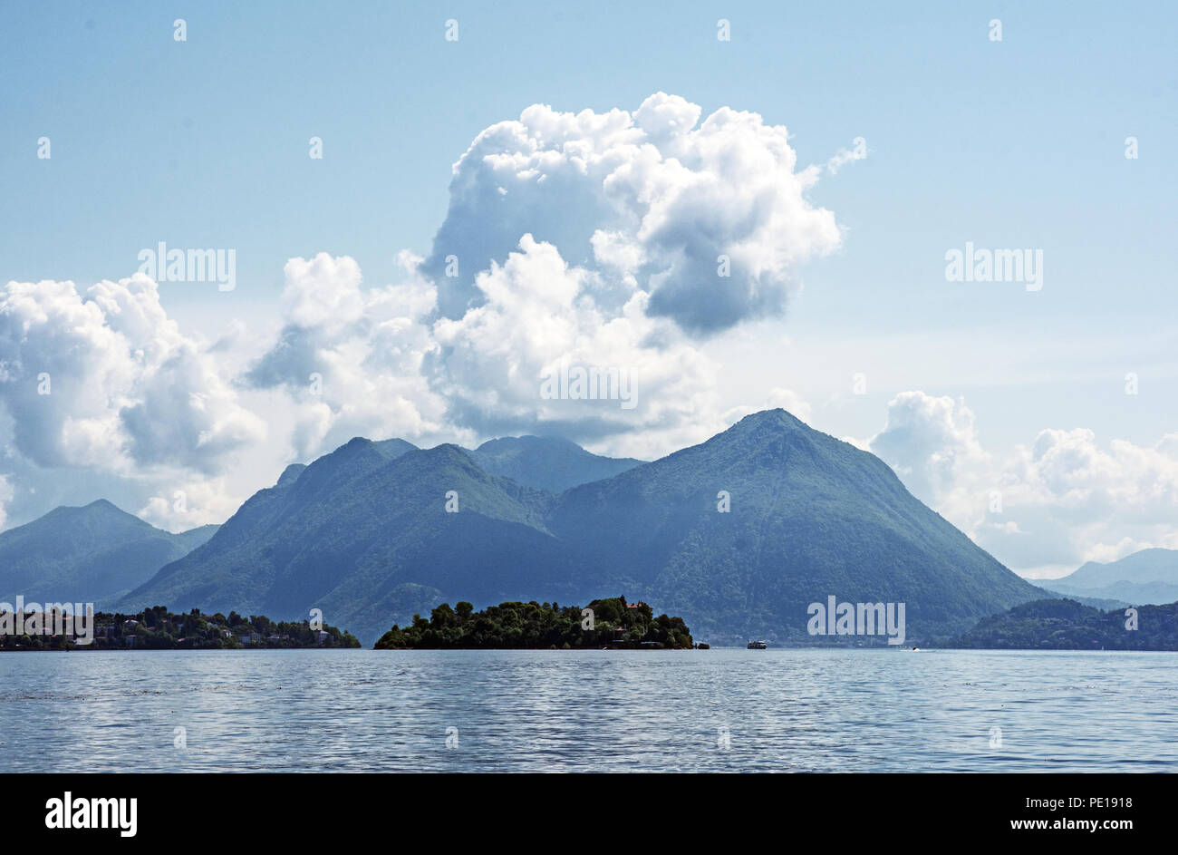 Vistas del Lago Maggiore en Baveno, Italia con Isola Madre y las montañas más allá. Las nubes cúmulos y cielo azul. Foto de stock