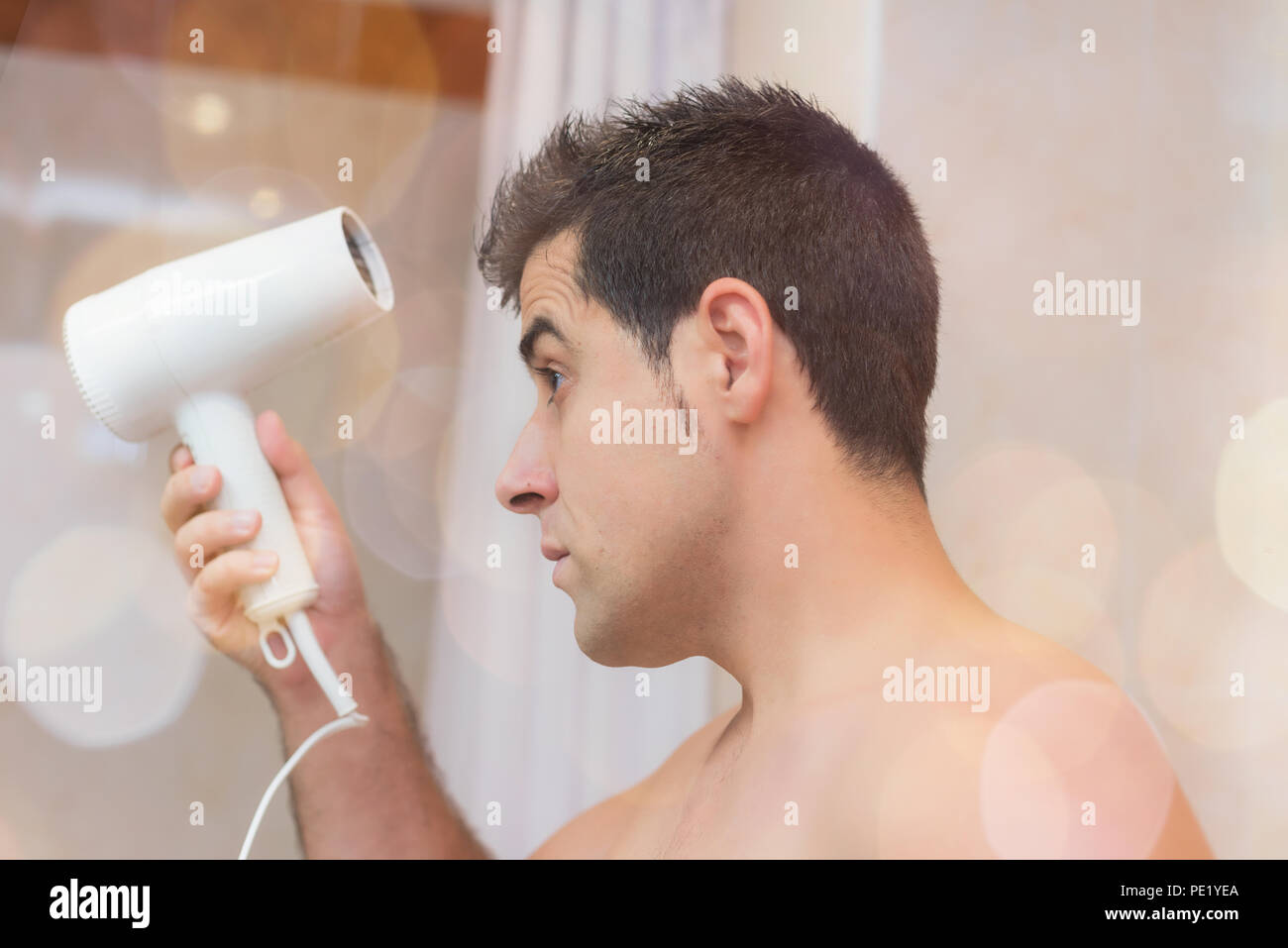 Guapo secar su cabello con un secador de pelo. Concepto de la belleza y el  cuidado del hombre Fotografía de stock - Alamy