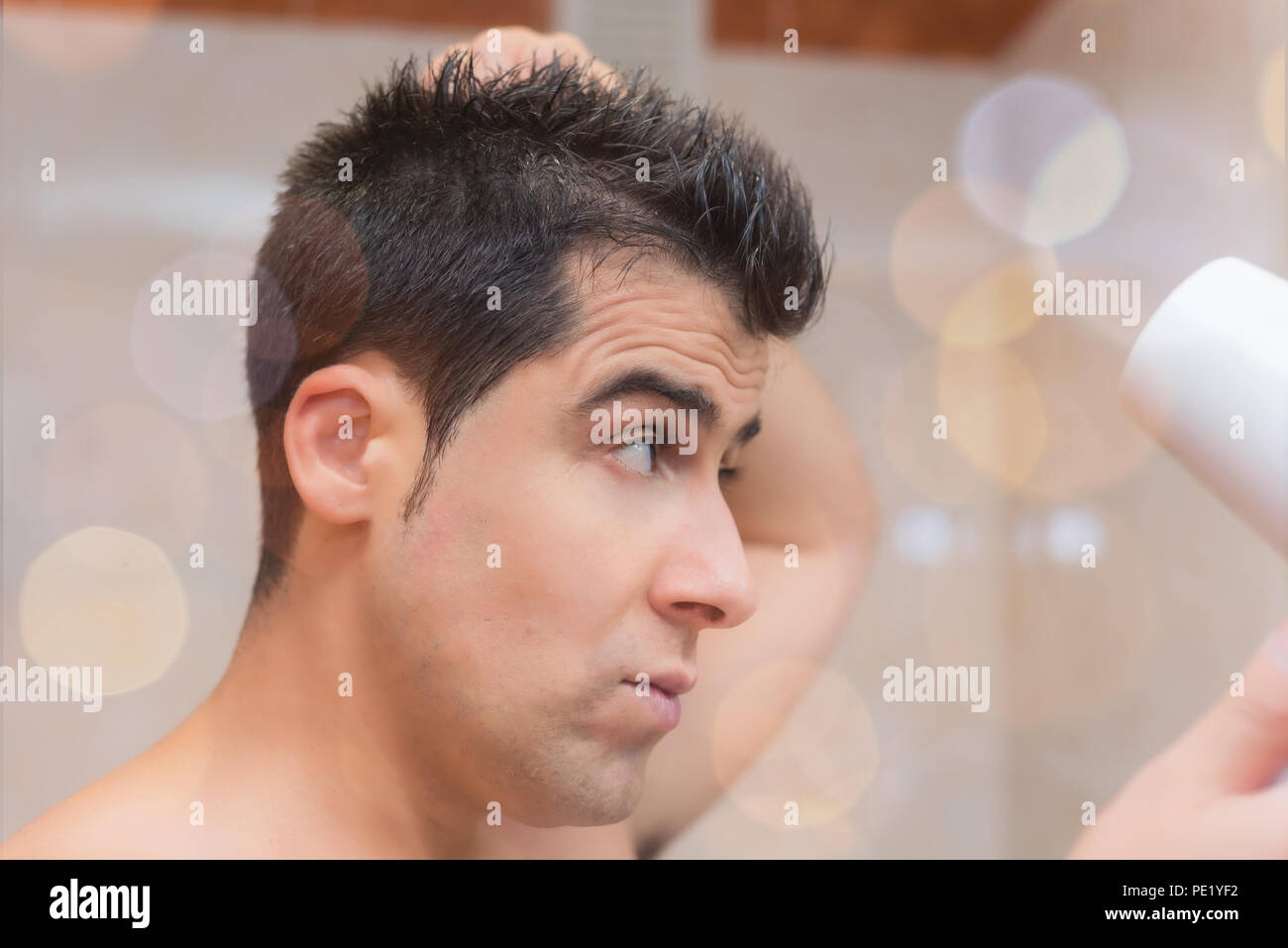 Guapo secar su cabello con un secador de pelo. Concepto de la belleza y el  cuidado del hombre Fotografía de stock - Alamy