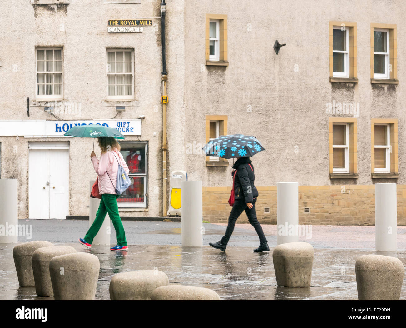 Holyrood, Edimburgo, Escocia, Reino Unido, 12 de agosto de 2018. El clima del Reino Unido: la lluvia y la niebla como los restos de la tormenta Debby golpea el capital no disuadir a los turistas en el Palacio de Holyrood. Dos mujeres que caminan la celebración de paraguas Foto de stock