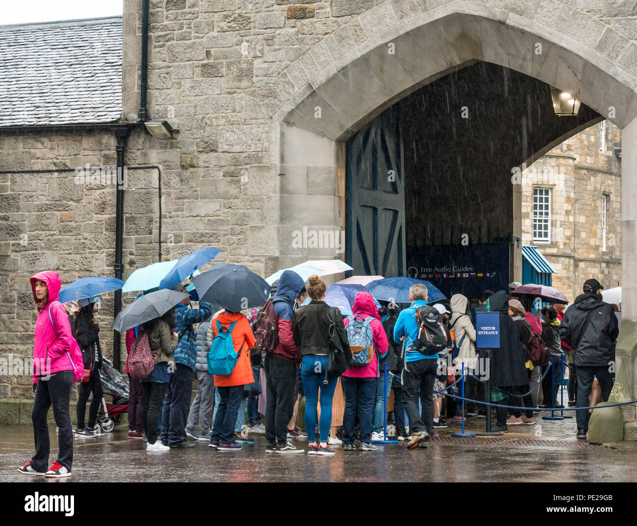 Holyrood, Edimburgo, Escocia, Reino Unido, 12 de agosto de 2018. El clima del Reino Unido: la lluvia y la niebla como los restos de la tormenta Debby golpea el capital no disuadir a los turistas en el Palacio de Holyrood. Personas haciendo cola para entrar en el palacio sosteniendo paraguas Foto de stock