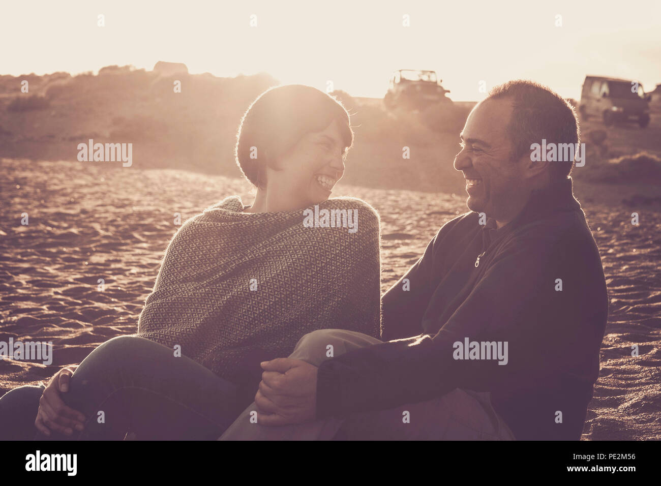 Preciosas La edad media de 40 años de edad par hombre y mujer caucásica se abrazaron y permanecer juntos en la playa, sentado en la arena y disfrutar de un golde un Foto de stock