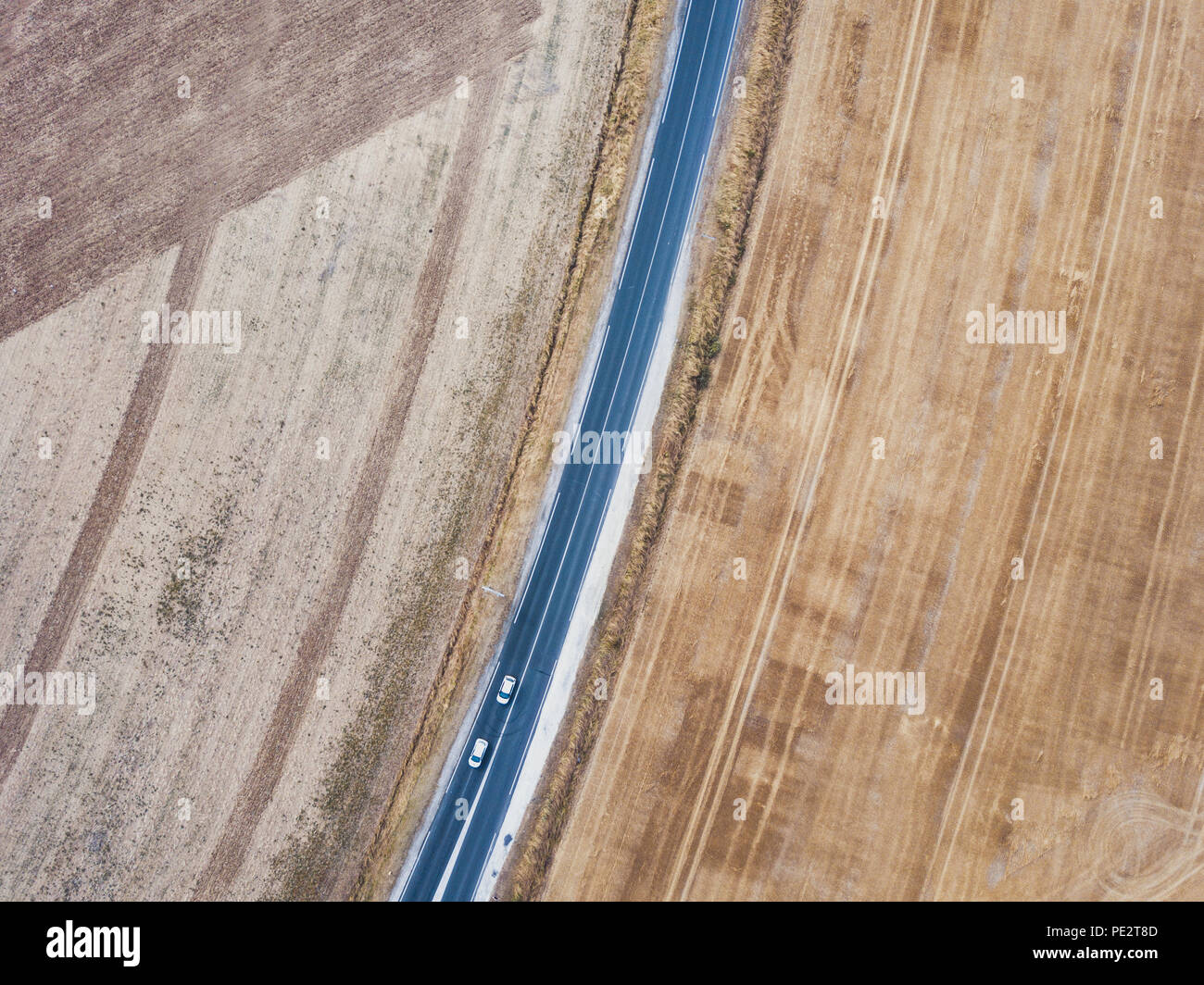 Vista aérea de la carretera asfaltada de drone, de arriba a abajo de dos automóviles circulando, paisaje de geometría Foto de stock