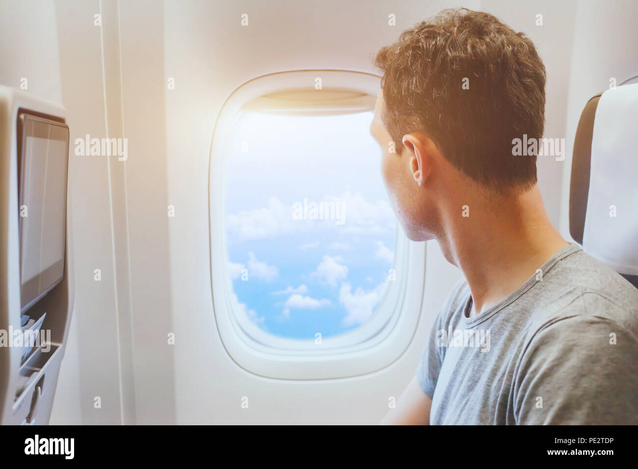 Pasajero del avión mirando en la ventana, los viajes internacionales, el hombre feliz turista disfrutar de vuelo en avión confortable Foto de stock
